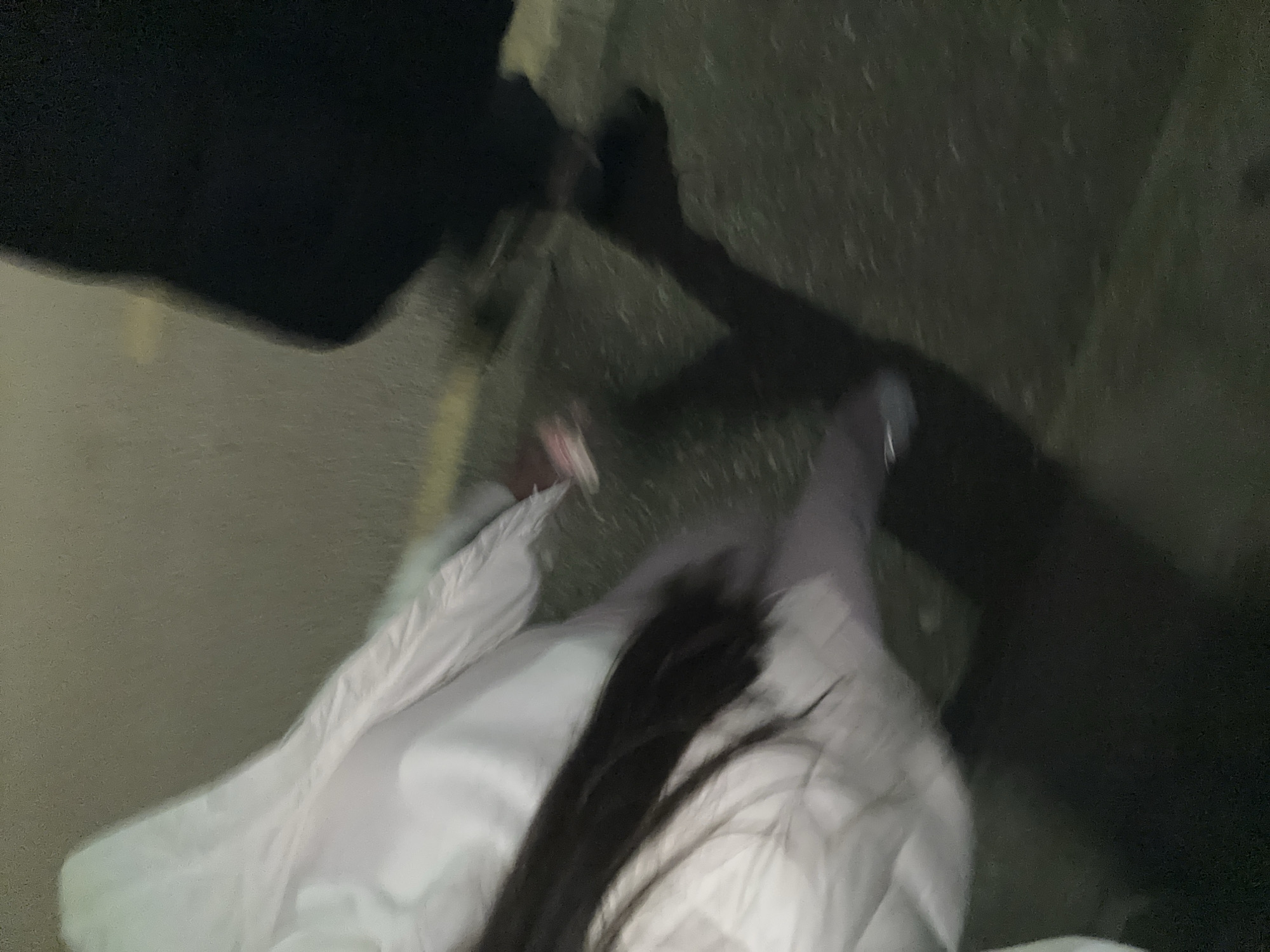 The image presents an obscured, nighttime perspective, possibly from a first-person viewpoint. A person wearing a white garment is partially visible, with a dark-haired individual standing close by. The surrounding environment appears to be an urban area, specifically Plovdiv, Bulgaria, characterized by a sidewalk or pavement and dark, indistinct shadows, typical of nighttime street scenes. The lack of clarity and limited details make it difficult to ascertain the exact location or any specific activity.