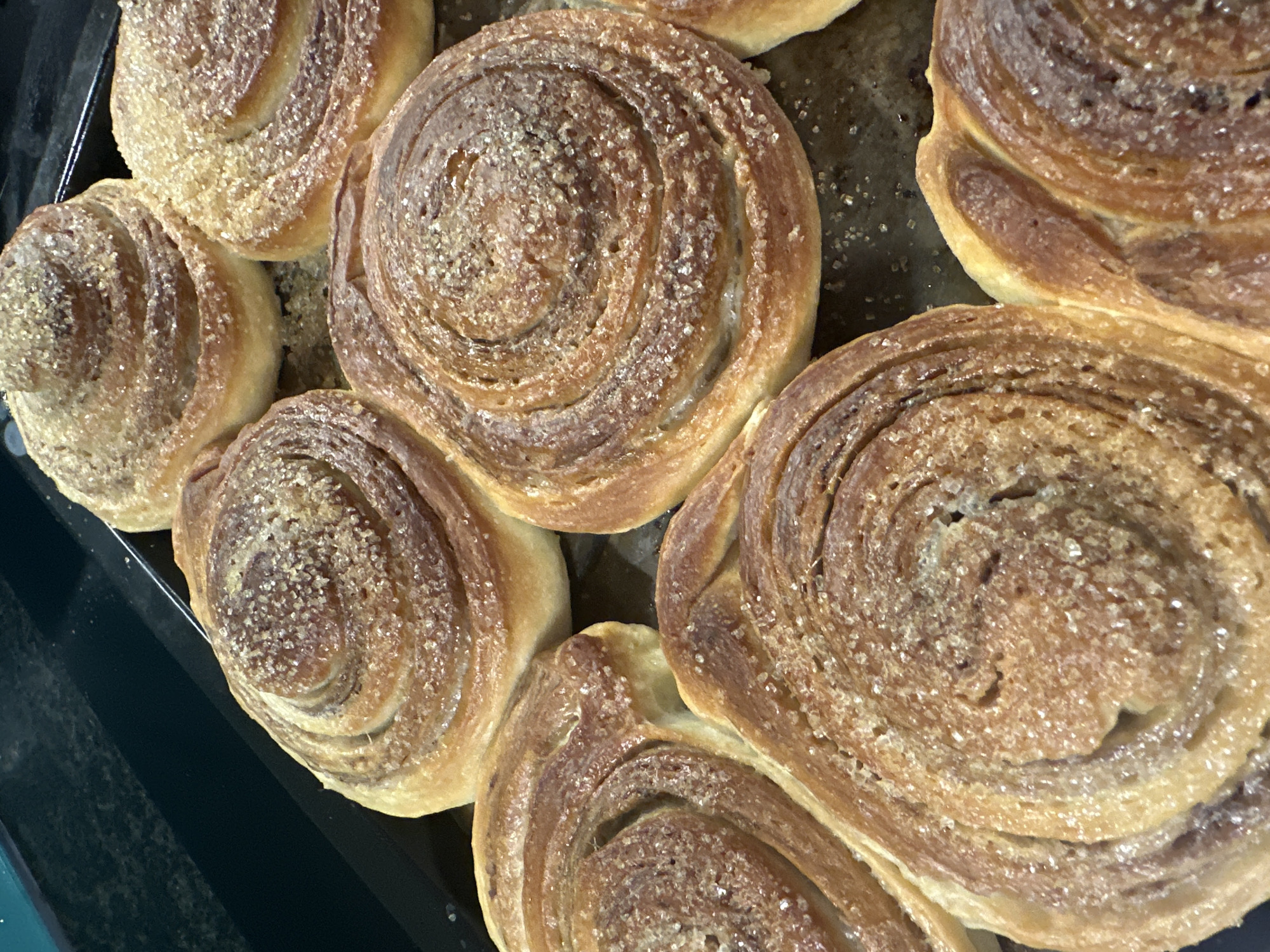 A tray of freshly baked cinnamon rolls sprinkled with sugar. The rolls are golden brown and arranged closely together. The setting appears to be a kitchen environment. No specific location information related to Bac Nha Trang Ward, Vietnam is discernible from the image.