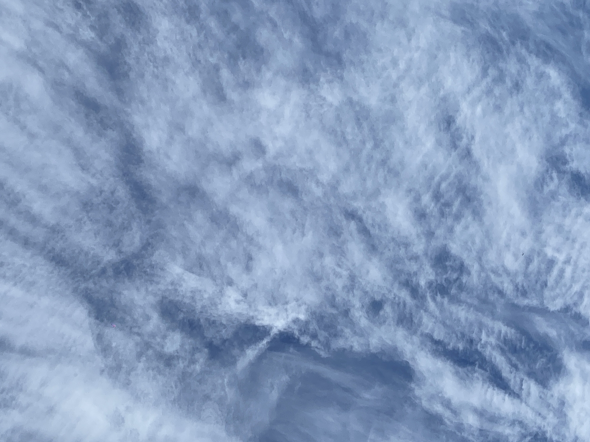 The image shows a sky with cirrus clouds. There is no identifiable information that confirms the location or suggests a city, people, actions, or objects. The scene appears to be an open sky area with natural cloud formations.