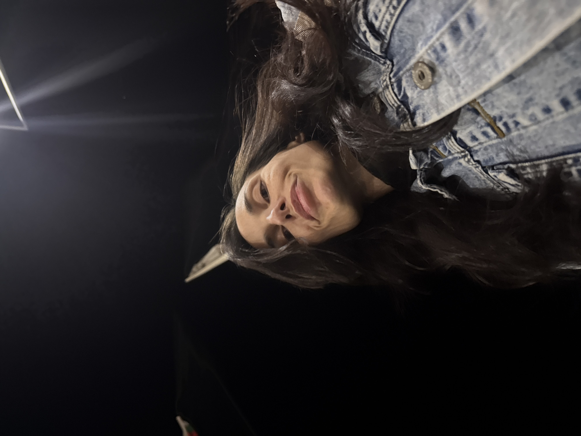 A low-angle shot depicts a woman with long, dark hair, wearing a denim jacket, against a dark background. She is looking downward. The location and any specific details related to Sofia, Bulgaria, cannot be determined.