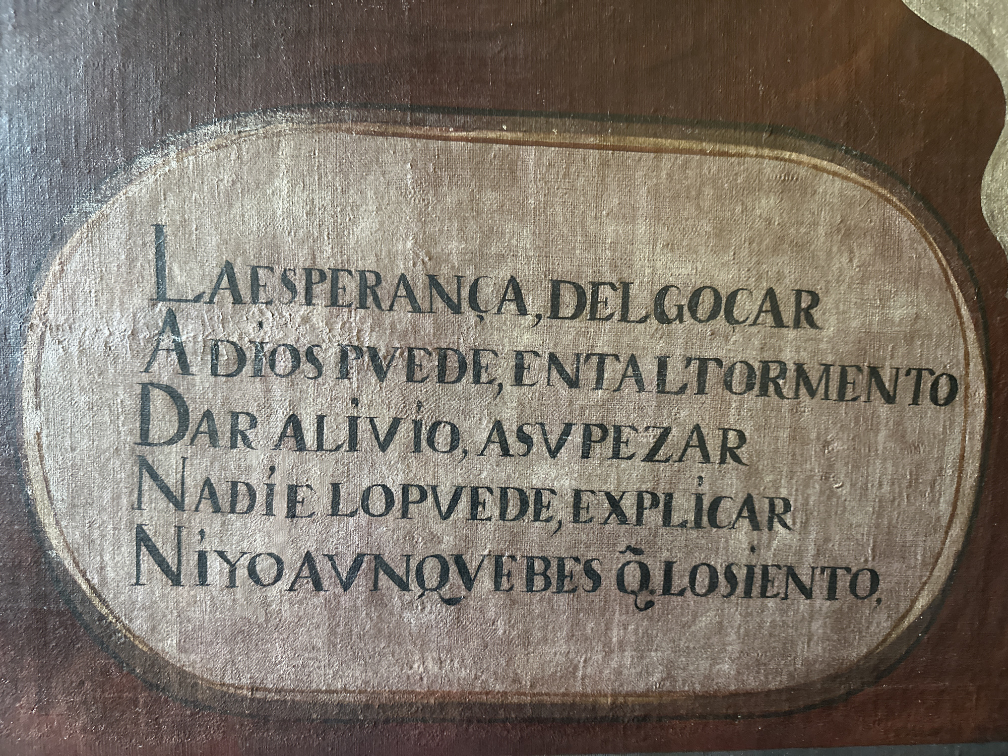 The image is a close-up of a rectangular, possibly old painting or inscription. The text within the image is in Spanish, with the following content:
"LAESPERANÇA, DEL GOCAR
A DIOS PVEDE, ENTALTORMENTO
DAR ALIVIO, ASVPEZAR
NADIE LOPVEDE, EXPLICAR
NIYOAVNOVE BES Ō LOSIENTO,"
The text is written in a simple, sans-serif font and is centered inside a dark-bordered, oval or rounded-rectangle frame. The background within the frame has a canvas-like texture. The border surrounding the frame appears to be aged and somewhat worn. The overall impression is that of an old, perhaps religious or philosophical saying painted on a textured surface.
The location of the original image is San Miguel Zinacantepec, Mexico.