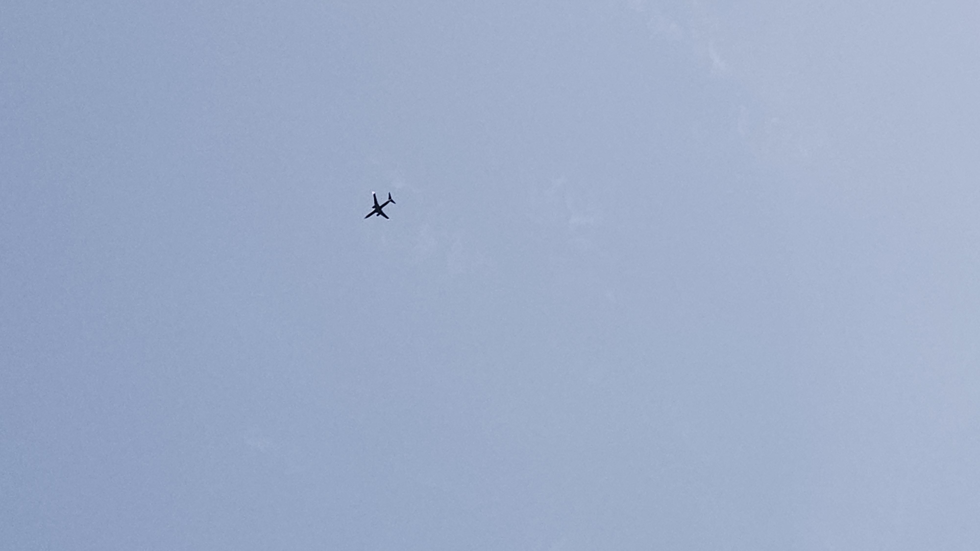 An airplane is flying in a blue sky. There are no other objects or subjects visible in the image. The location in the city of Unknown, Unknown is unknown.