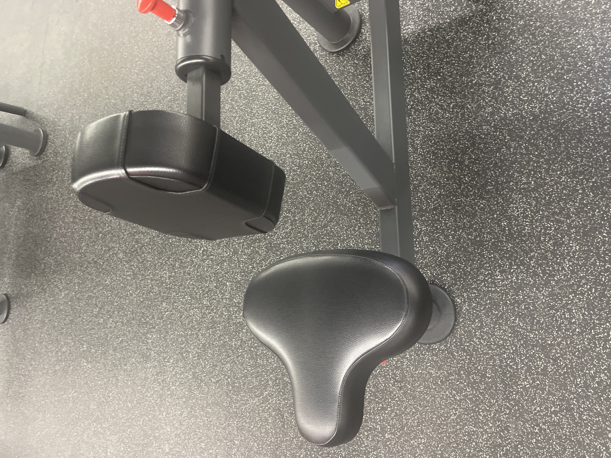 The image shows a piece of exercise equipment, specifically a seated chest press machine. The machine features a black seat, chest pad, and gray metal frame. The background appears to be a gray rubberized floor, typical of a gym setting. The image does not provide any information about the location in Plovdiv, Bulgaria. There are no people, actions, or interactions in the image.