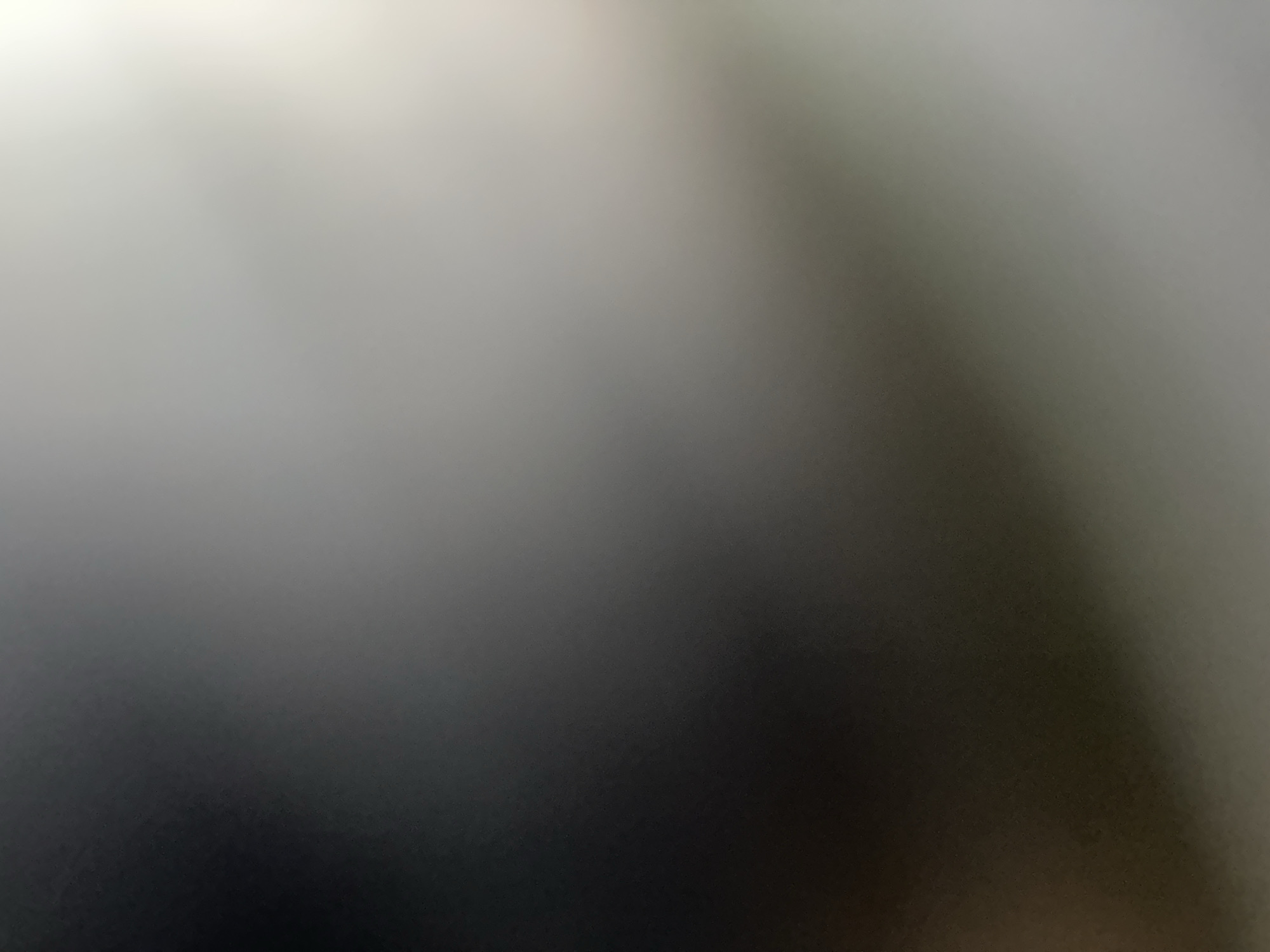 This is a close-up, abstract photograph featuring a gradient of colors ranging from a soft, bright white in the upper left corner to dark grey and black in the lower portion. The image lacks distinct subjects, objects, or a discernible scene. There is no clear activity or event taking place.
Notable details are limited due to the abstract nature of the image. There are no obvious cues about the time of day, weather, or specific location. The image conveys a sense of diffused light and shadow, with a slight blur or out-of-focus effect throughout. No text is visible. Given the context of Belgrade, Serbia, this image could be a detail from an interior or exterior surface, or perhaps an abstract representation of light and shadow play in an urban environment.