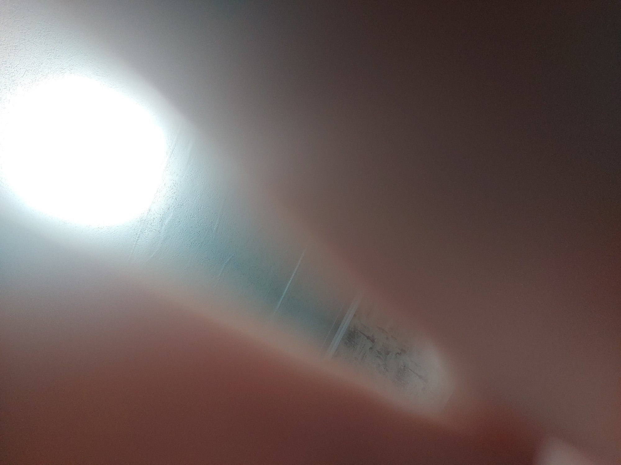 The image is severely out of focus and overexposed. A bright, diffused light source dominates the upper left of the frame, obscuring any details behind it. Faint lines and textures are vaguely visible stretching from the light source towards the lower right. The overall color is a blend of light grays, blues, and muted pinks or browns. It is impossible to discern specific objects or subjects, and no information about a location in Chaikovsky, Russia can be extracted from the image.