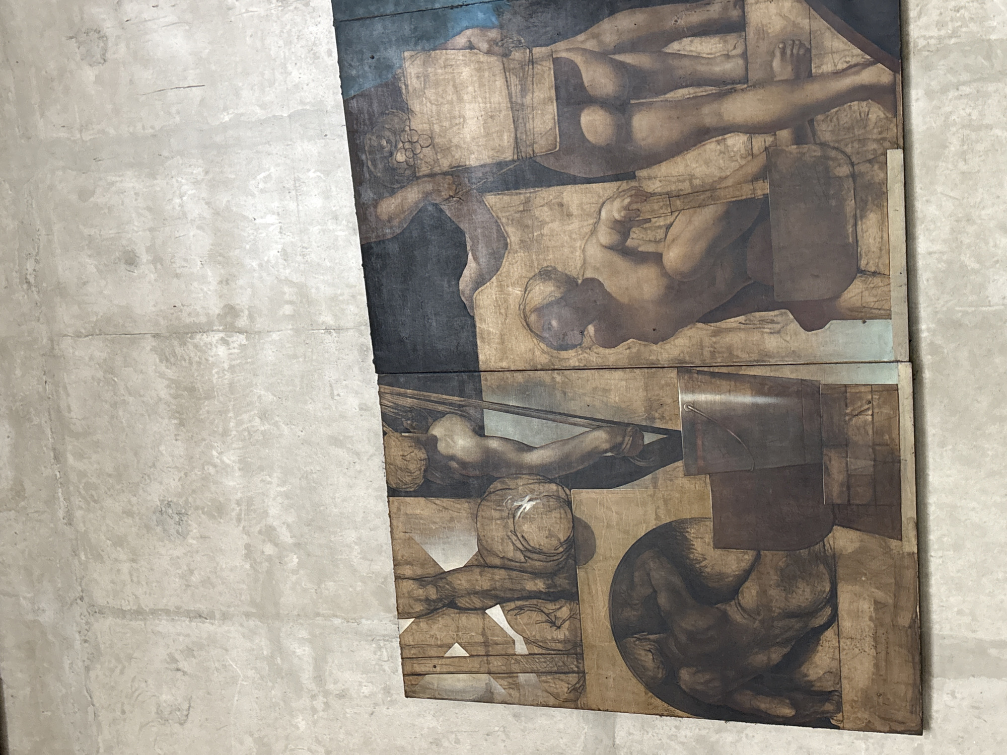 This image shows a section of a large mural painting depicting several nude figures in what appears to be a scene of labor or artistic creation. The painting is rendered in earthy tones, with a style that suggests classical or Renaissance influence. The figures are muscular and their poses are dynamic, conveying a sense of effort and movement. In the foreground, one figure is crouched, looking towards another figure who stands behind them. The standing figure is holding a large object that resembles a block or a canvas. There are also architectural elements and what appear to be tools or containers, such as a bucket. The painting is mounted on a wall with a textured, light-colored surface, likely concrete or plaster.
This mural is located in the **Edifício Copan**, a prominent skyscraper in the city center of São Paulo, Brazil. Specifically, it is found in the atrium of the building, near the ground floor. The artwork is part of the building's design, intended to enhance the architectural experience for its occupants and visitors.