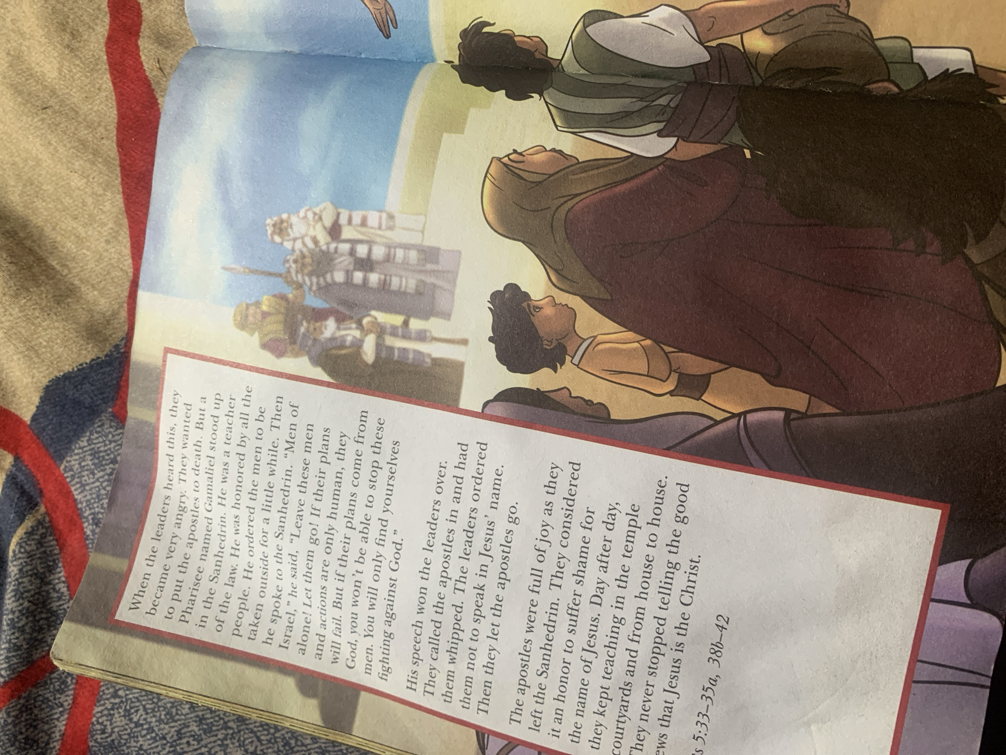 This media file is a close-up shot of an open book, likely a children's Bible, featuring an illustration and text. The illustration depicts a group of people in ancient-style clothing, appearing to be listening to or observing something. The style is cartoonish and colorful, with warm tones dominating the artwork. The people are rendered with distinct features and varied expressions, suggesting a narrative scene.
The text on the page is in English and appears to be a religious story, likely from the New Testament. It recounts an event where leaders are angry with apostles, and a respected teacher named Gamaliel intervenes. The text describes the apostles being whipped and warned not to speak in Jesus' name, but they later rejoice in suffering for Jesus and continue to teach about him. Specific Bible verses are cited at the end: Acts 5:33-35a, 38b-42.
The setting implied by the text is ancient Israel, within the context of religious and judicial proceedings (Sanhedrin). While no specific time of day or weather is indicated, the indoor or possibly outdoor setting of a religious gathering is suggested. The emotions conveyed by the text range from anger and authority to courage and joy. The image itself is slightly tilted, and the book is placed on a patterned fabric, possibly a blanket or cloth, with red and blue stripes visible along the left edge.