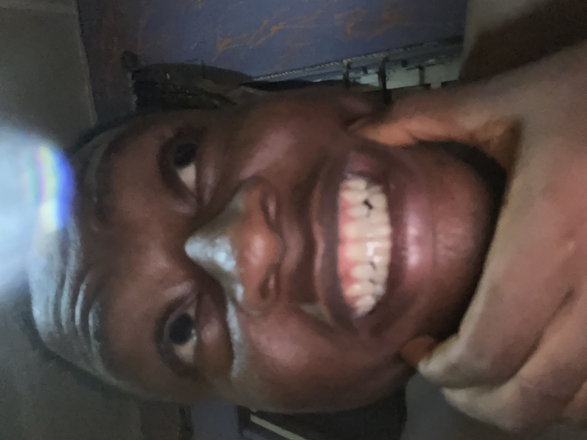 A close-up photo shows an African woman's face with a large smile, her teeth visible. A hand is touching her cheek. The location is possibly Ikorodu, Nigeria based on a hypothetical scenario. Other background elements are indistinct.