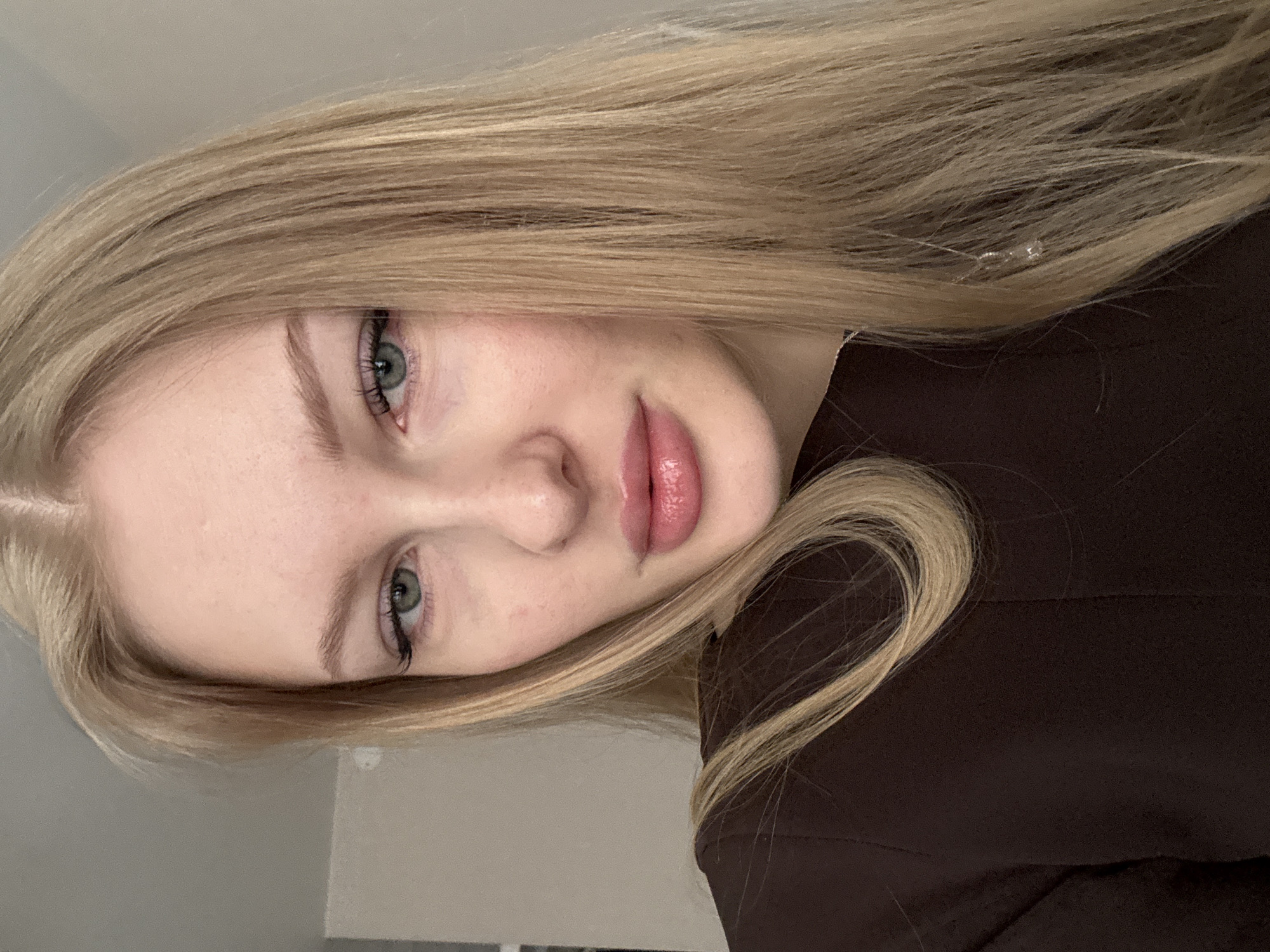 A close-up, portrait-oriented photo features a fair-skinned, young woman with light blonde hair wearing a brown garment. The subject is oriented at an angle with her face tilted towards the viewer. Her eyes are light-colored. The location of Perm, Russia is not discernible from the image.
