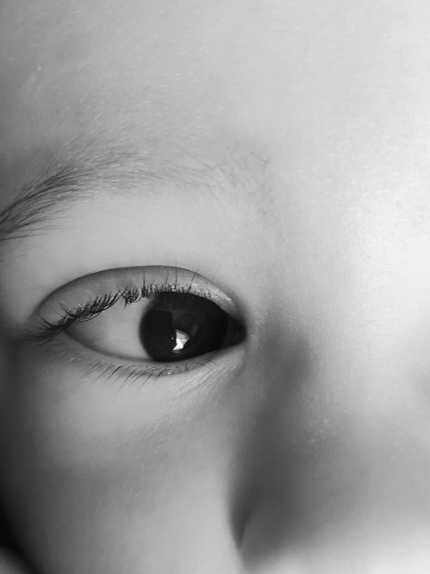 A close-up, black and white photograph depicts a human eye. The eyebrow is visible above the eye, and eyelashes frame the upper and lower lids. A light reflection is visible in the pupil of the eye. There is no contextual information in the image to determine location, including the city of Chaikovsky, Russia.