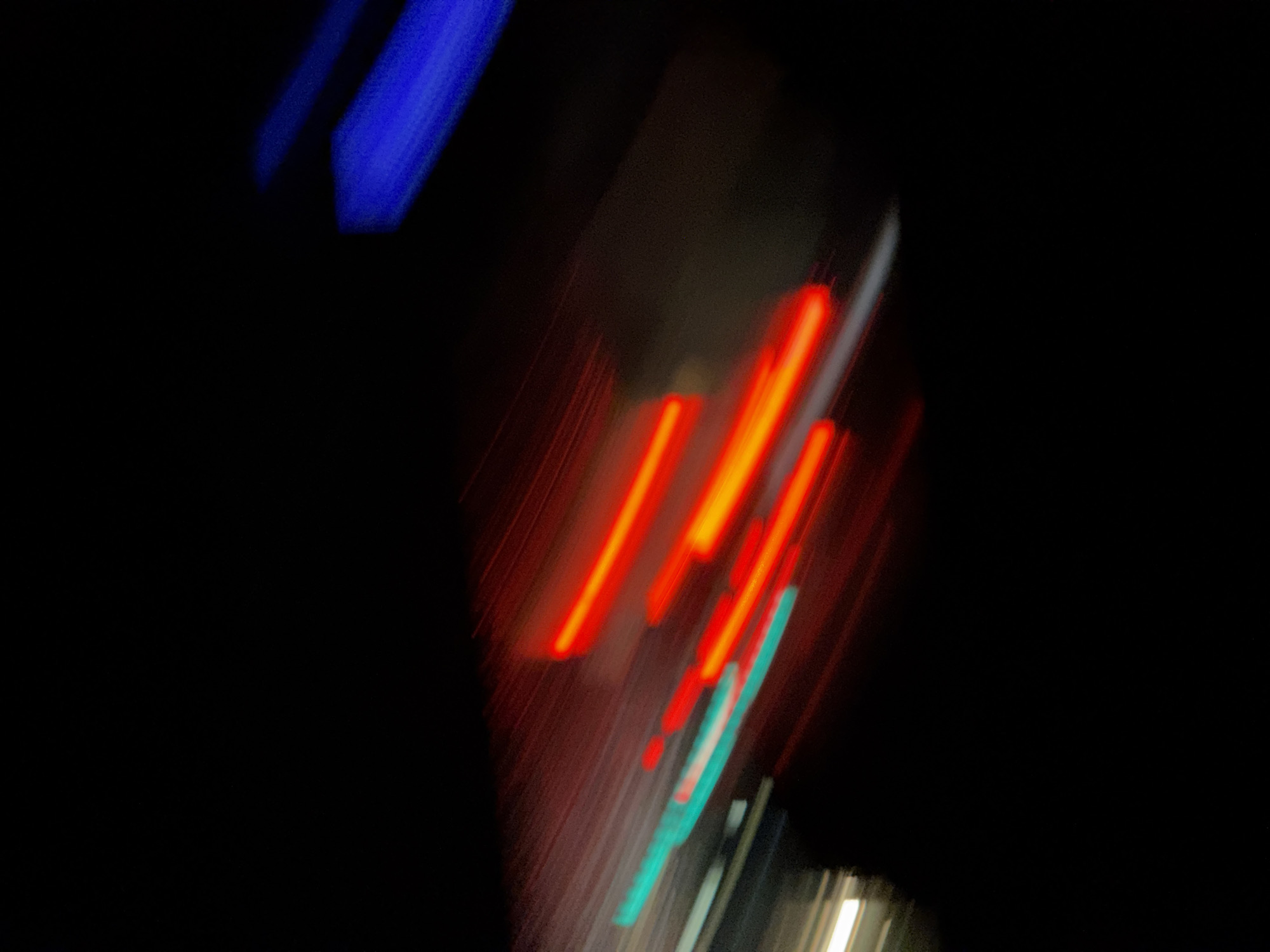 The image shows blurred streaks of blue, red, and teal lights against a dark background. The streaks are diagonal and appear to be captured with a long exposure or while in motion. Based on the prompt's instructions, the location is Kursk, Russia. However, without clearer imagery, any further detail or forensic information will be speculation. No people or objects (other than the lights) are discernible. No actions or interactions can be described. The environment is dark.
