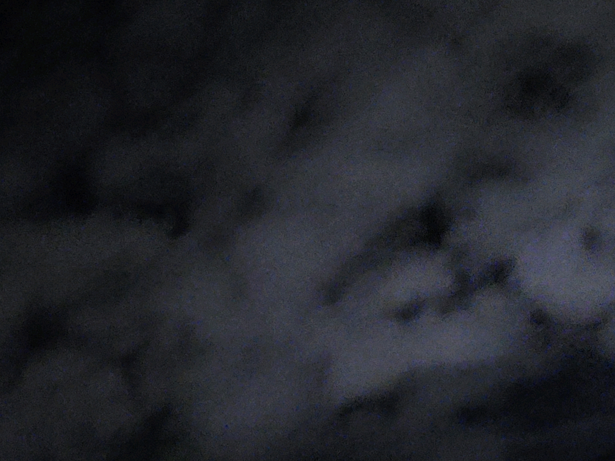 The image is a dark, grainy, abstract photograph that appears to depict clouds or smoke. There are no discernible objects, people, or locations. The overall impression is one of obscurity and low visibility. Without any visual cues or context, it is impossible to determine the location in the city of Ozolnieki, Latvia, or any specific details about the scene.