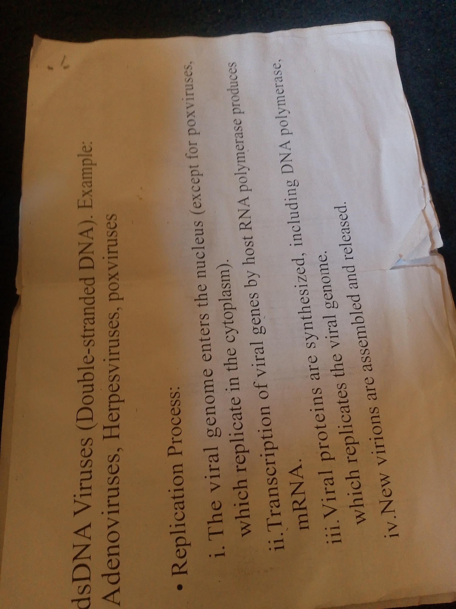 This media file contains a close-up shot of a piece of paper with text printed on it. The paper is laid flat on a dark, textured surface, possibly fabric. The text is oriented such that the paper appears to be at an angle, suggesting it might be a page from a notebook or a document that has been scanned or photographed.
The visible text is in English and discusses DNA viruses, their replication process, and examples such as adenoviruses and herpesviruses. Specific points mention the entry of the viral genome into the nucleus, transcription of viral genes, synthesis of viral proteins including DNA polymerase, and the assembly and release of new virions.
There are no people, animals, or specific environmental cues like weather or time of day visible in the image. The focus is entirely on the printed text and the paper it is on. The background is dark and out of focus, providing no additional context about the setting other than it is likely an indoor environment where documents are handled. There are no identifiable location cues related to Jalingo, Nigeria.