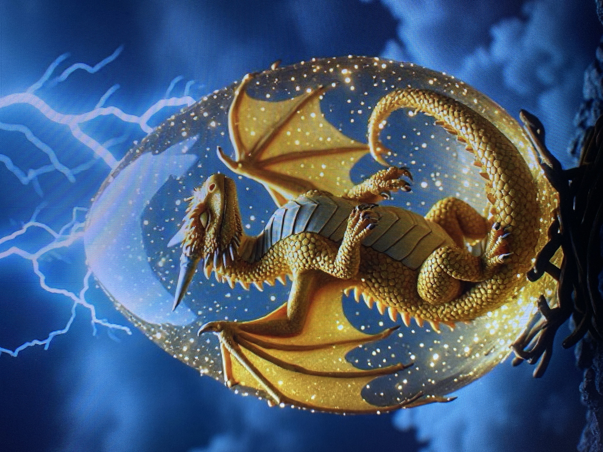 A golden dragon is depicted emerging from an iridescent egg. The dragon is positioned centrally within the egg, with its wings outstretched and its head turned to the side. The egg is surrounded by swirling blue clouds and illuminated by streaks of lightning. Small, bright specks of light are scattered throughout the scene, adding a magical quality. The dragon has detailed scales and a spiky crest along its back. The image appears to be a digital artwork or illustration. There is no discernible connection to the city of Yerevan, Armenia.