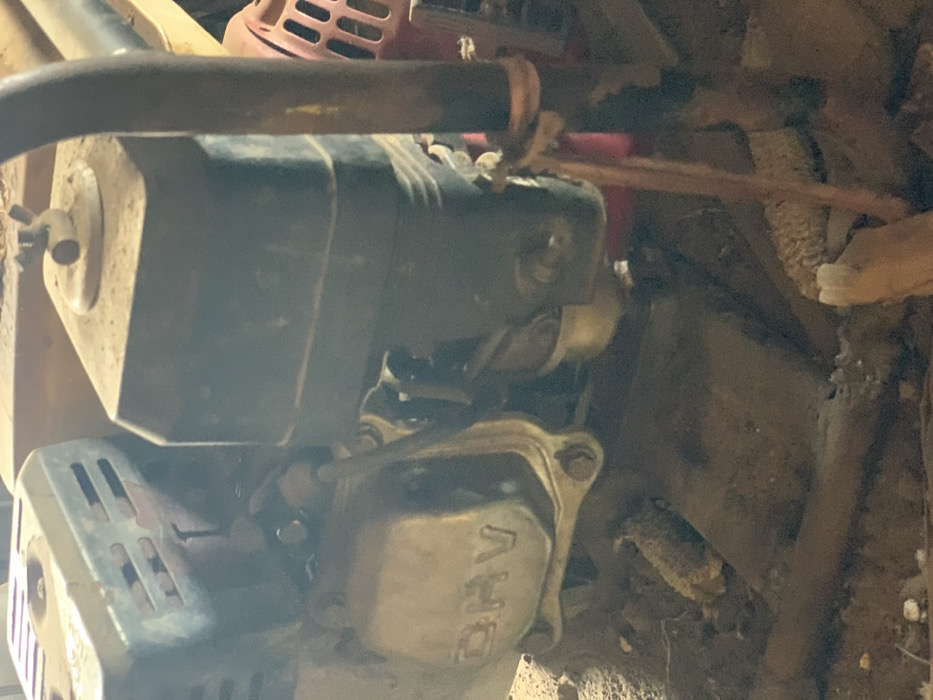 The image shows a close-up of the engine of a small, gas-powered machine. The engine is mostly obscured by dirt and rust, with some of the metal parts visible. The engine is located in Egbeda, Nigeria, at the coordinates 7.12 latitude and 5.362 longitude. The image suggests that the machine is in a state of disrepair. It is difficult to say anything further about the scene, as the image provides only a limited view.