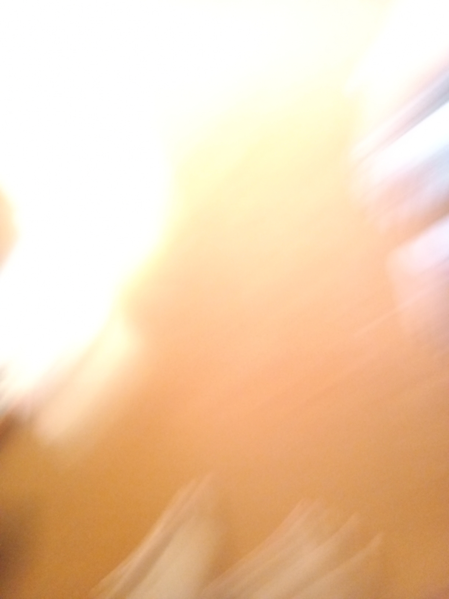 The image is an abstract, out-of-focus depiction of light and color, lacking any discernible objects or recognizable environmental features. There are no people, subjects, or actions visible. The colors range from bright white and yellow on the left to a gradient of orange and brown towards the right, with streaks of white and light blue suggesting motion blur or light refractions. There are no specific details that can place this image in Subang, Indonesia, or any other specific location.