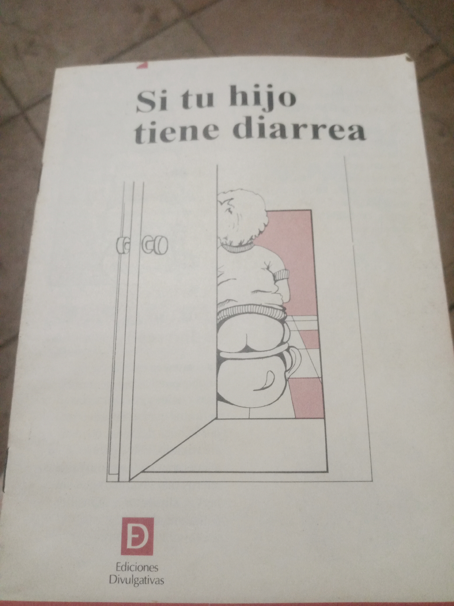 The image shows the cover of a book titled "Si tu hijo tiene diarrea". The cover features a line drawing of a child sitting on a potty, with the child's back to the viewer. The child is wearing a sweater and pants, and their legs are bent. The potty is white with a handle. To the left of the drawing, there is a representation of a door with two doorknobs, labeled "CG CO". Below the drawing, there is a logo with the letter "D" inside a red square, and the text "Ediciones Divulgativas". The background is white. The book is lying on a textured surface that appears to be tile, possibly in a home or office setting. There is no indication of the city of Santa Ana, Venezuela, or any other specific location.
