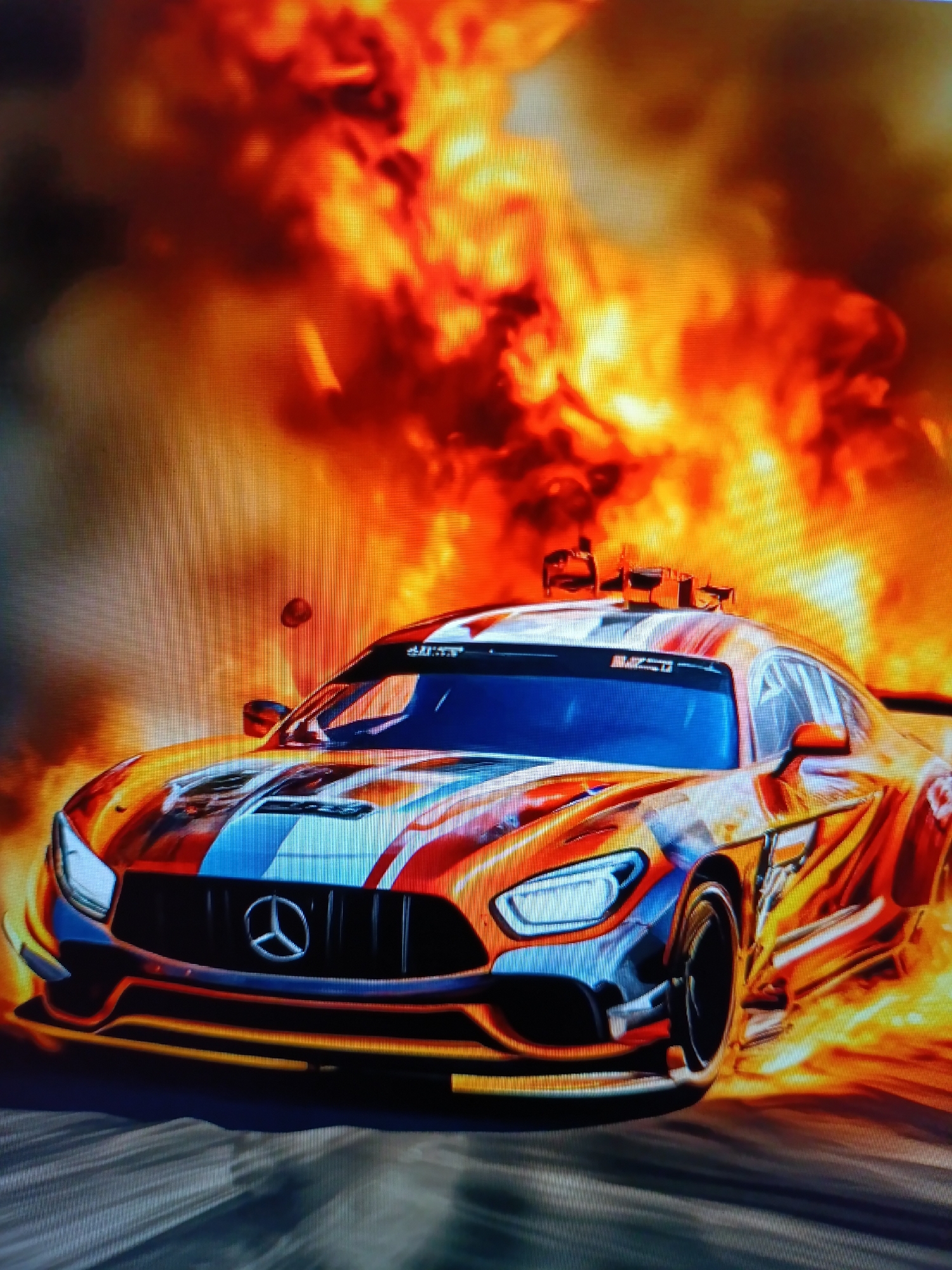 An image depicts a high-performance car, likely a Mercedes-AMG GT, with a vibrant, fiery livery, positioned in the foreground. The car is shown in motion, with a blurred background suggesting speed. Behind the vehicle, a large, intense fire erupts, dominating the upper portion of the frame. The flames are depicted in various shades of orange, red, and yellow, with swirling smoke adding to the dramatic effect. The car's design features prominent racing stripes in white and blue, contrasting with the fiery graphics. The overall scene conveys a sense of intense action and power.