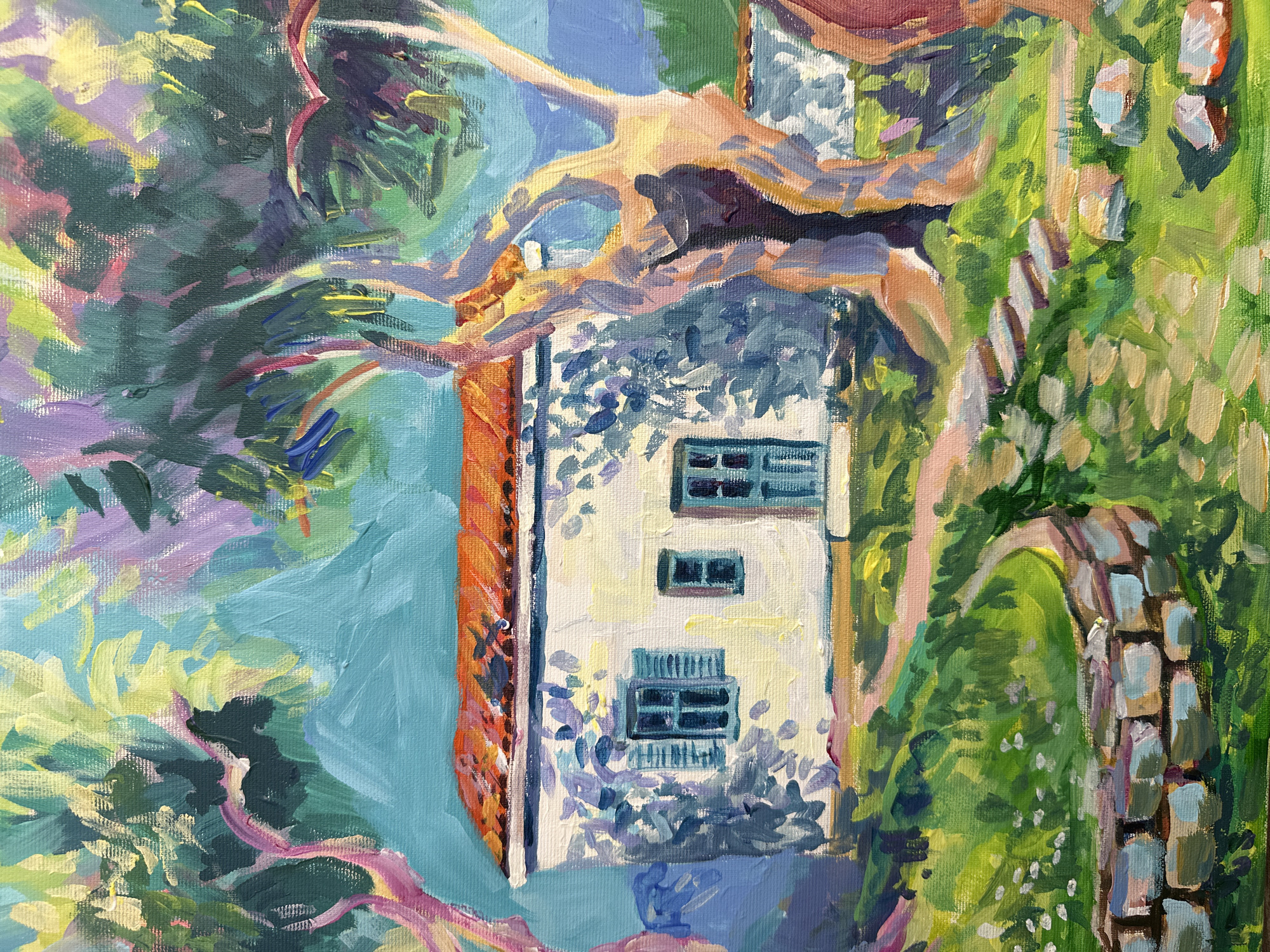 This is an oil painting of a small, white house with a red tile roof, nestled amongst lush green foliage and trees. The house has blue shutters on its windows and a blue door. A stone path with stepping stones leads to the house through a grassy yard with scattered wildflowers and a low stone wall. The painting features vibrant colors and an impressionistic style, with visible brushstrokes. The background is a blur of blues and greens, suggesting a natural landscape. The overall impression is one of a serene, rural setting.