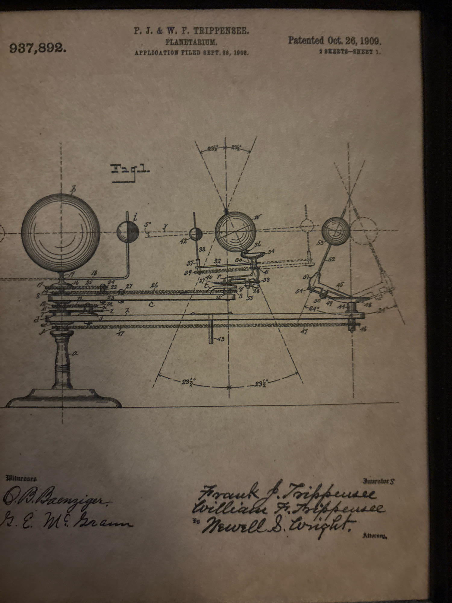 This image is a scan of a patent document for a planetarium. The document is from the United States, patented on October 26, 1909, with an application filed on September 28, 1908. The patent number is 937,892. The document includes a detailed technical drawing of the planetarium, labeled "Fig. 1". The drawing shows various mechanical components with numbered labels, indicating its complex nature. The document also lists the inventors as P. J. & W. F. Trippensee and William F. Trippensee, with Newell S. Wright listed as the attorney. Two witnesses are also listed: O. B. Raenziger and R. E. McCreann. There are no people or specific actions depicted in the drawing itself, as it is a technical illustration. The environment is that of a scanned historical document. The provided crops highlight specific sections of the document, including the patent information, the technical drawing, and the signature sections. There is no information within the image that indicates a specific location in the city of South Bradenton, United States of America.