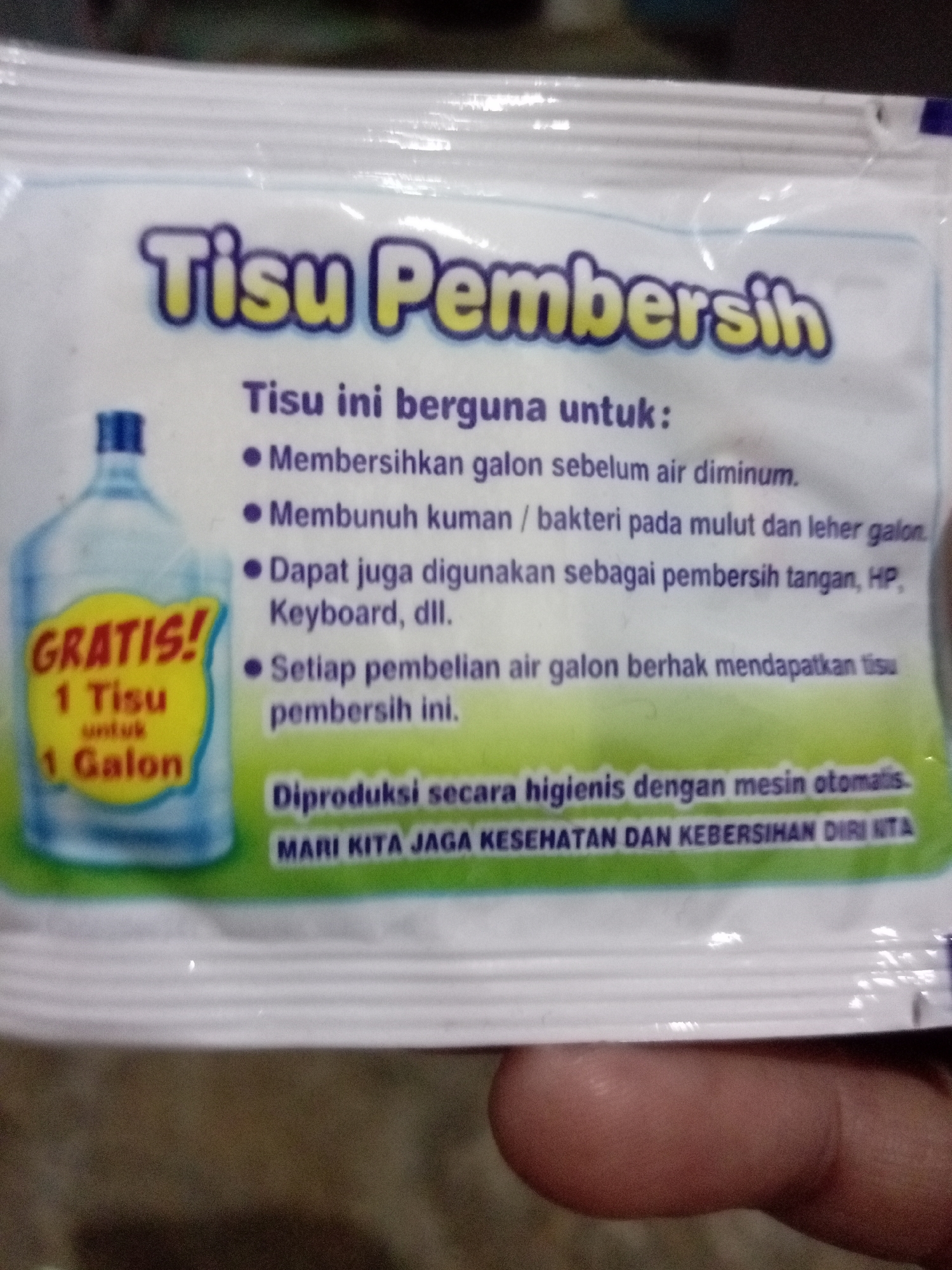 The image shows a close-up of a wet wipe package with Indonesian text. The brand name "Tisu Pembersih" is prominently displayed at the top. The text indicates the product is useful for cleaning gallon bottles before drinking water, killing germs on mouths and necks of gallon bottles, and can also be used as a hand and HP cleaner. There is also a promotional message about receiving 1 tissue for every gallon purchase. The bottom of the package states it is produced hygienically with an automated machine and encourages maintaining personal health and cleanliness. A graphic of a gallon water bottle with a "GRATIS! 1 Tisu untuk 1 Galon" sticker is on the left side of the package. The image is not specific to Batam, Indonesia, and no information about the city is present.