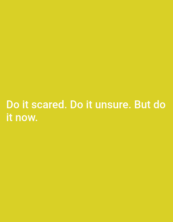 The image displays a digital graphic with white text centered on a solid, uniform deep yellow background. The text reads, "Do it scared. Do it unsure. But do it now." The first line of text is "Do it scared. Do it unsure." and the second line is "But do it now." The image does not depict any people, subjects, objects, actions, or interactions within a physical environment, nor does it show a specific location in a city. It is purely a textual message presented on a colored digital canvas.