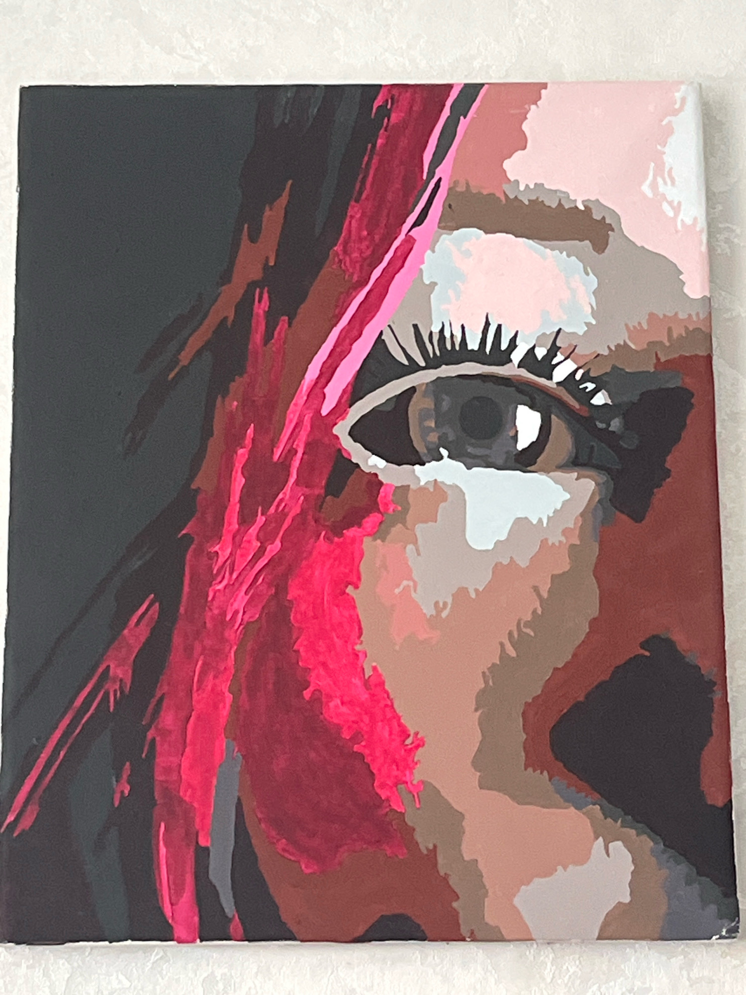 This is a close-up painting of a human eye and part of a face, rendered in a stylized, abstract manner with bold blocks of color. The eye is the central focus, with a dark pupil, a brown iris, and long, spiky eyelashes. The skin tones are depicted with various shades of pink, beige, and brown, creating a mosaic-like effect. To the left of the eye, there are streaks of bright pink and dark brown, suggesting hair or fabric. The background is predominantly black. The painting appears to be on a canvas. There is no indication of the city of Шевырялово, Russia, or any other environmental or geographical context.