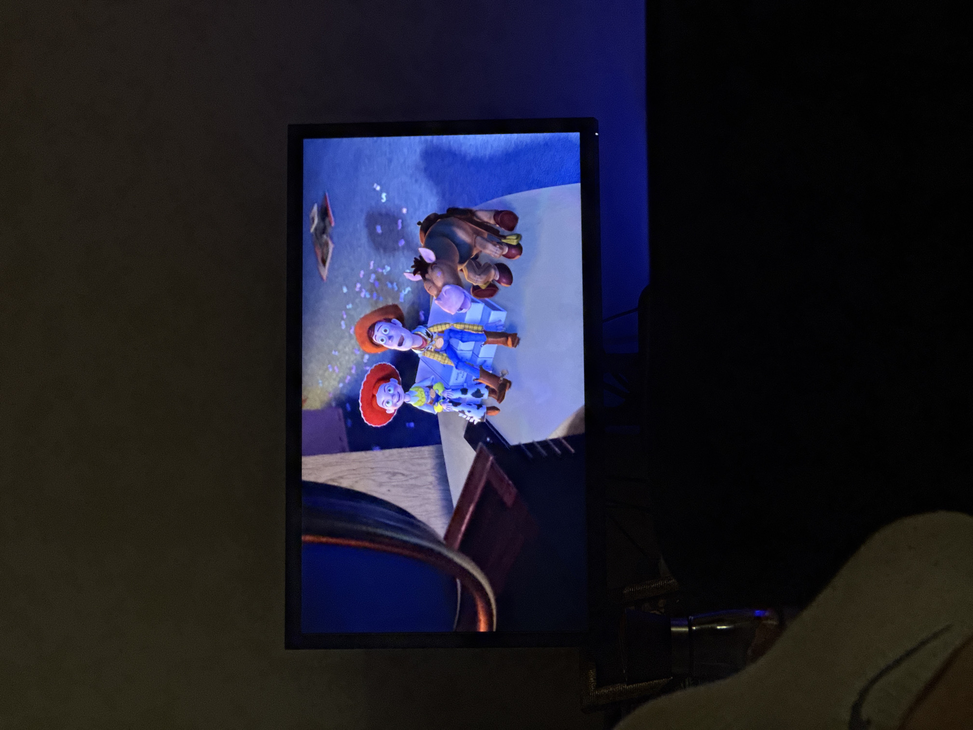 The image shows a television screen displaying a scene from the movie "Toy Story," featuring the characters Woody, Jessie, and Bullseye. The TV is positioned indoors, with surrounding walls and objects visible. No specific location in Varna, Bulgaria, can be determined from the image.