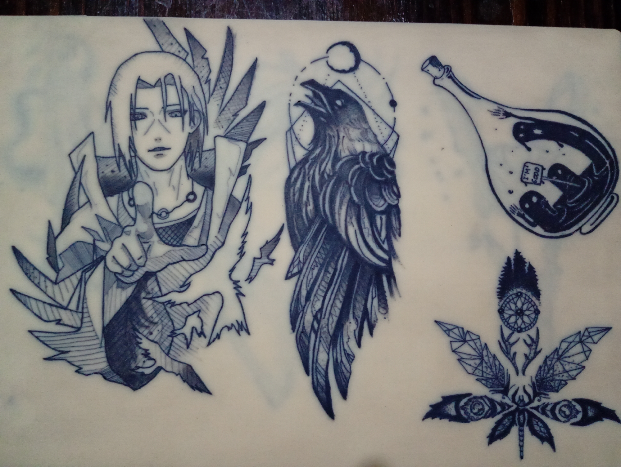 The image shows a tattoo practice sheet with four distinct designs. The first, on the left, is an anime-style character with a dark-colored robe and a hand gesture. Next to it is a raven with geometric shapes in the background. To the right of the raven is a glass bottle containing shadowy figures and a sign that reads "I'm Good". The last design, at the bottom right, is a stylized marijuana leaf with eyes and other symbolic elements. There is no information to suggest the image has anything to do with Roza, Bulgaria.