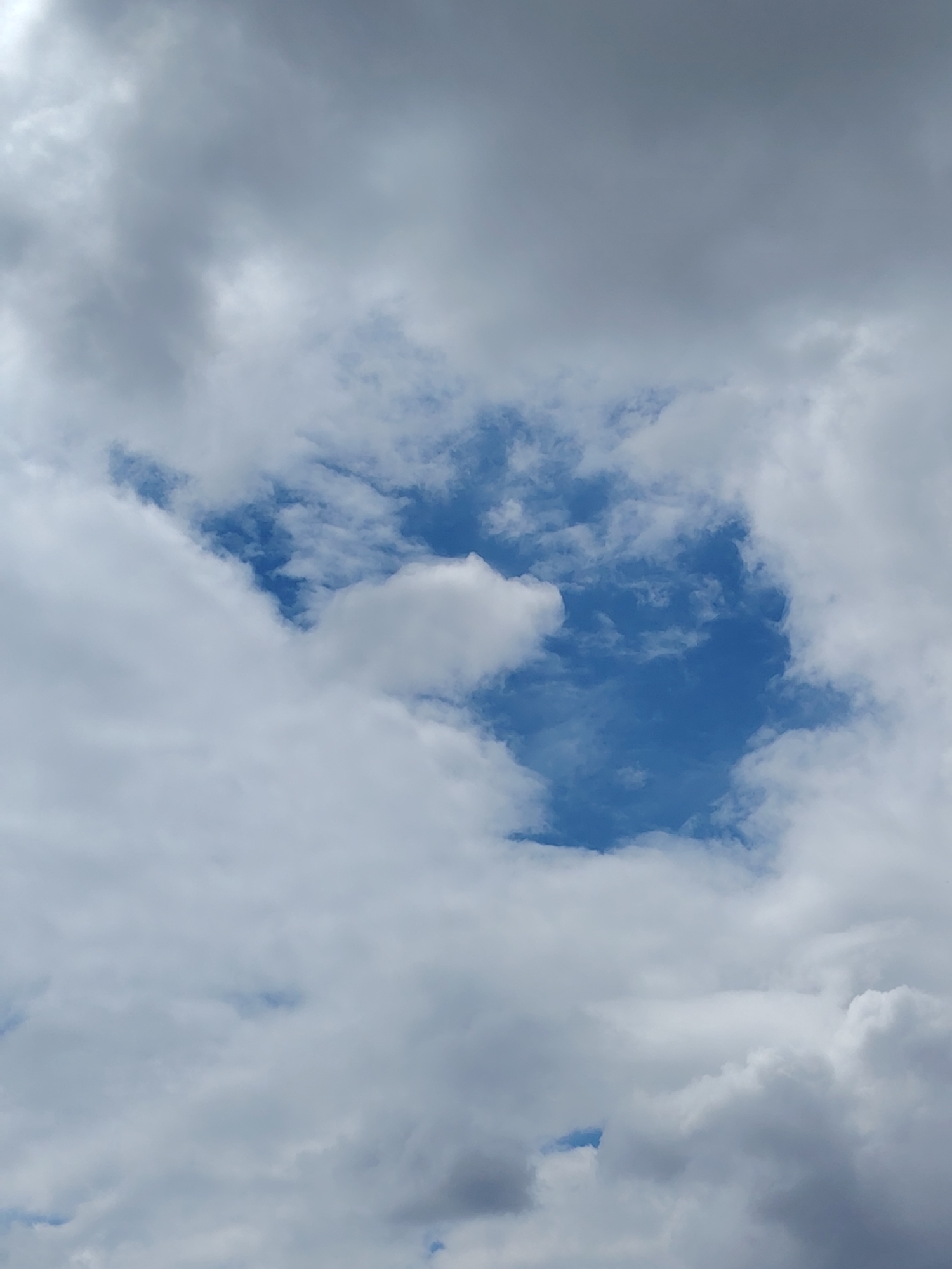 The image shows a sky filled with clouds, with a clear patch of blue sky in the center. The clouds are a mix of white and gray, suggesting a partly cloudy day. The scene is an outdoor environment with no visible people, subjects, objects, actions, or interactions. The location in Kagal'nitskaya, Russia, is irrelevant to the visual content of the image.