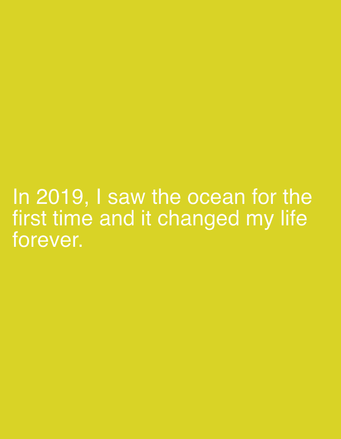 The image features white text on a yellow background. The text reads: "In 2019, I saw the ocean for the first time and it changed my life forever." The text is centrally located within the frame.