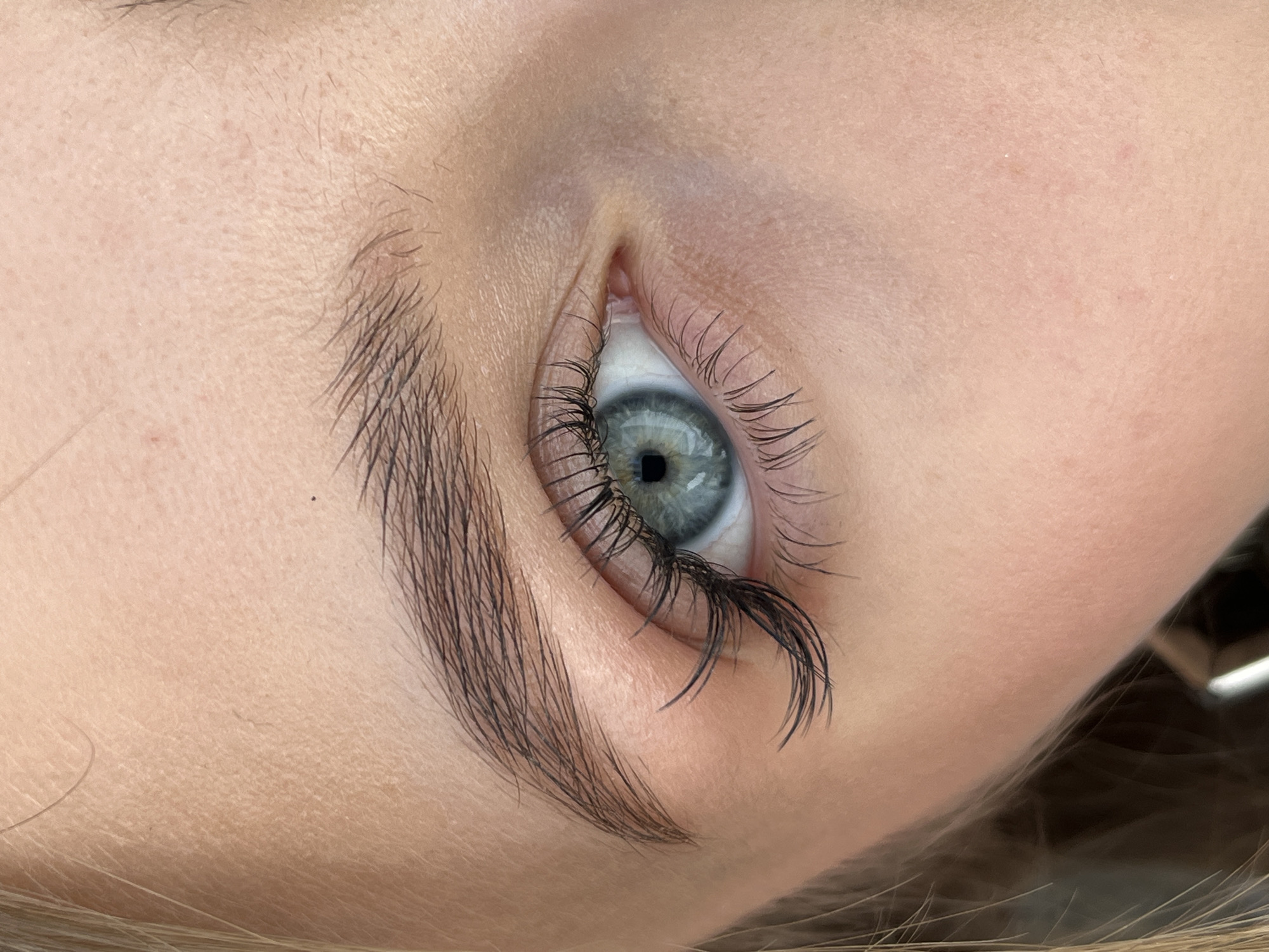 An eye and eyebrow of a person are visible. The eye is light blue/grey, and the eyebrow is dark and thick. Skin texture around the eye is visible. The location is unknown, including the city of Фоки, Russia.