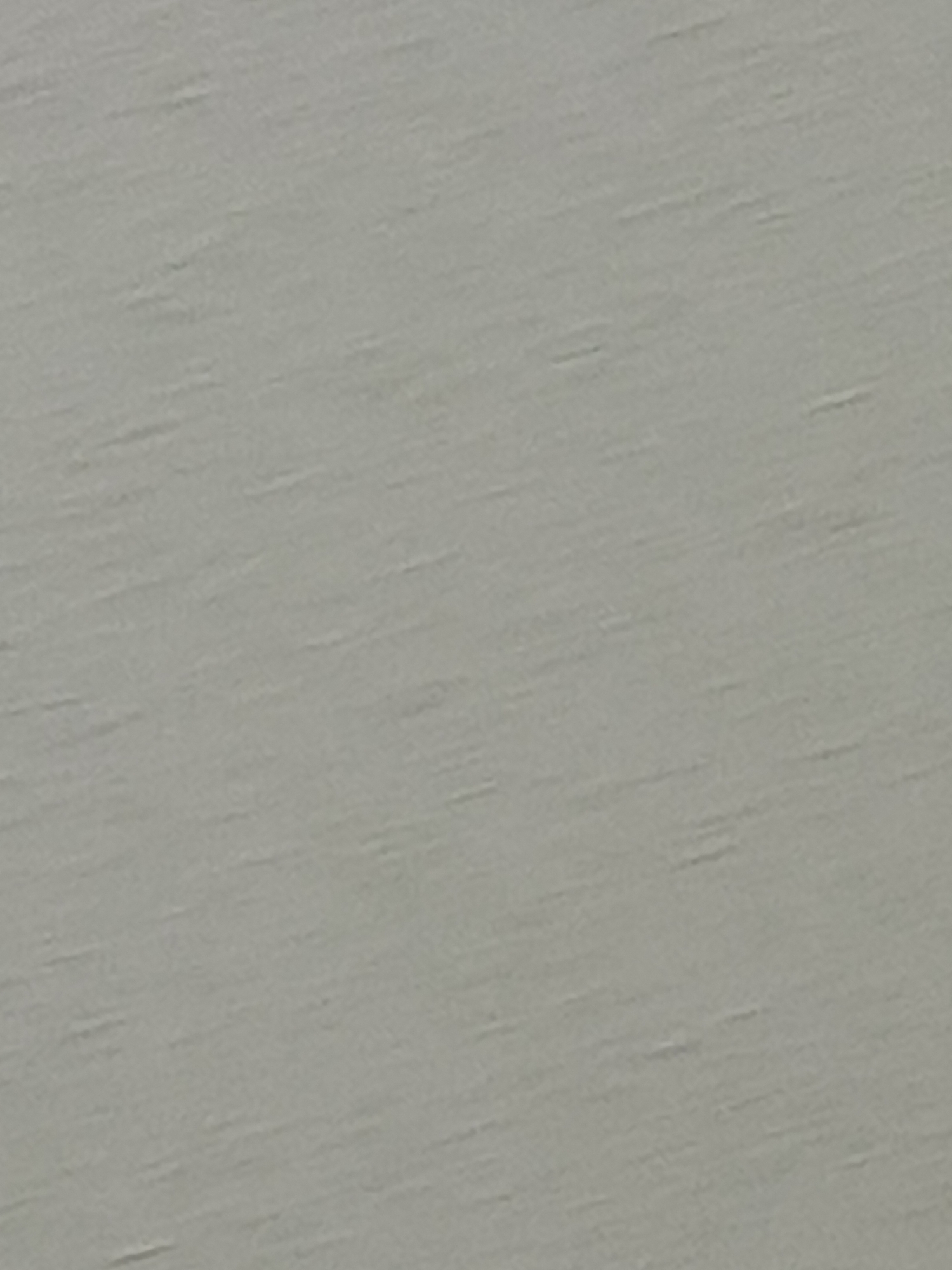 The image shows a close-up of a gray, textured surface. The surface appears to have slight diagonal striations or irregularities. No people, objects, or city locations are discernible in the image.
