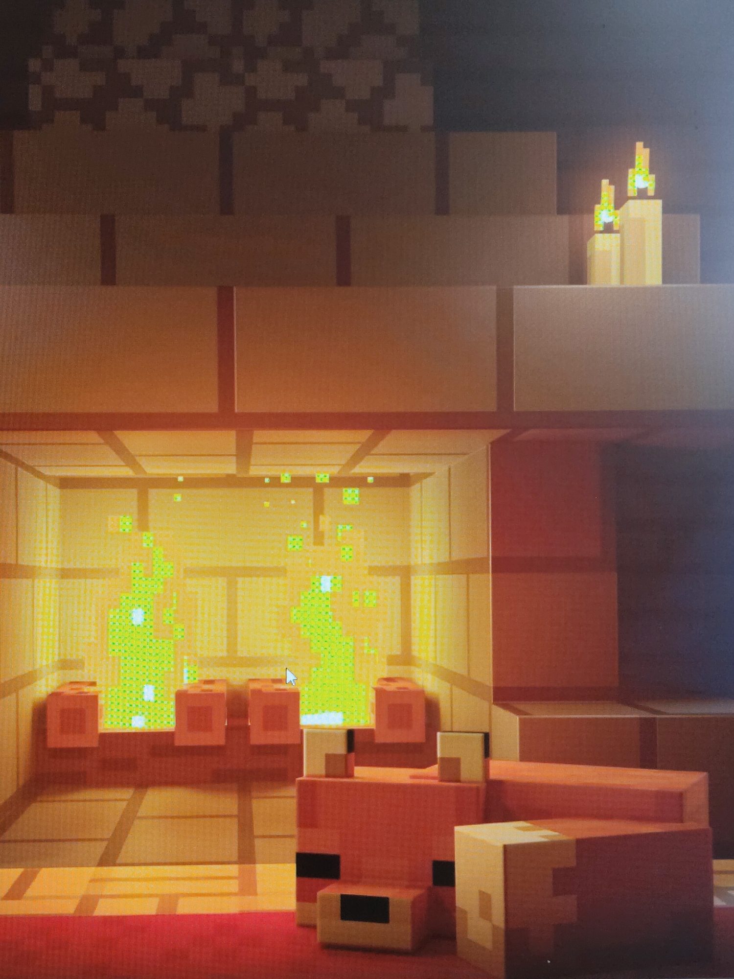 The image shows a pixelated rendering reminiscent of a Minecraft build, featuring a cozy scene with a fireplace. Inside the fireplace, there is a green fire burning. In front of the fireplace, there is a pixelated fox figure resting. Above the fireplace on a ledge, there are two lit candles. The walls and general structure are built with orange blocks. There is also pixelated furniture to the right of the fox. The image does not contain information that permits the determination of its location in Perm, Russia.