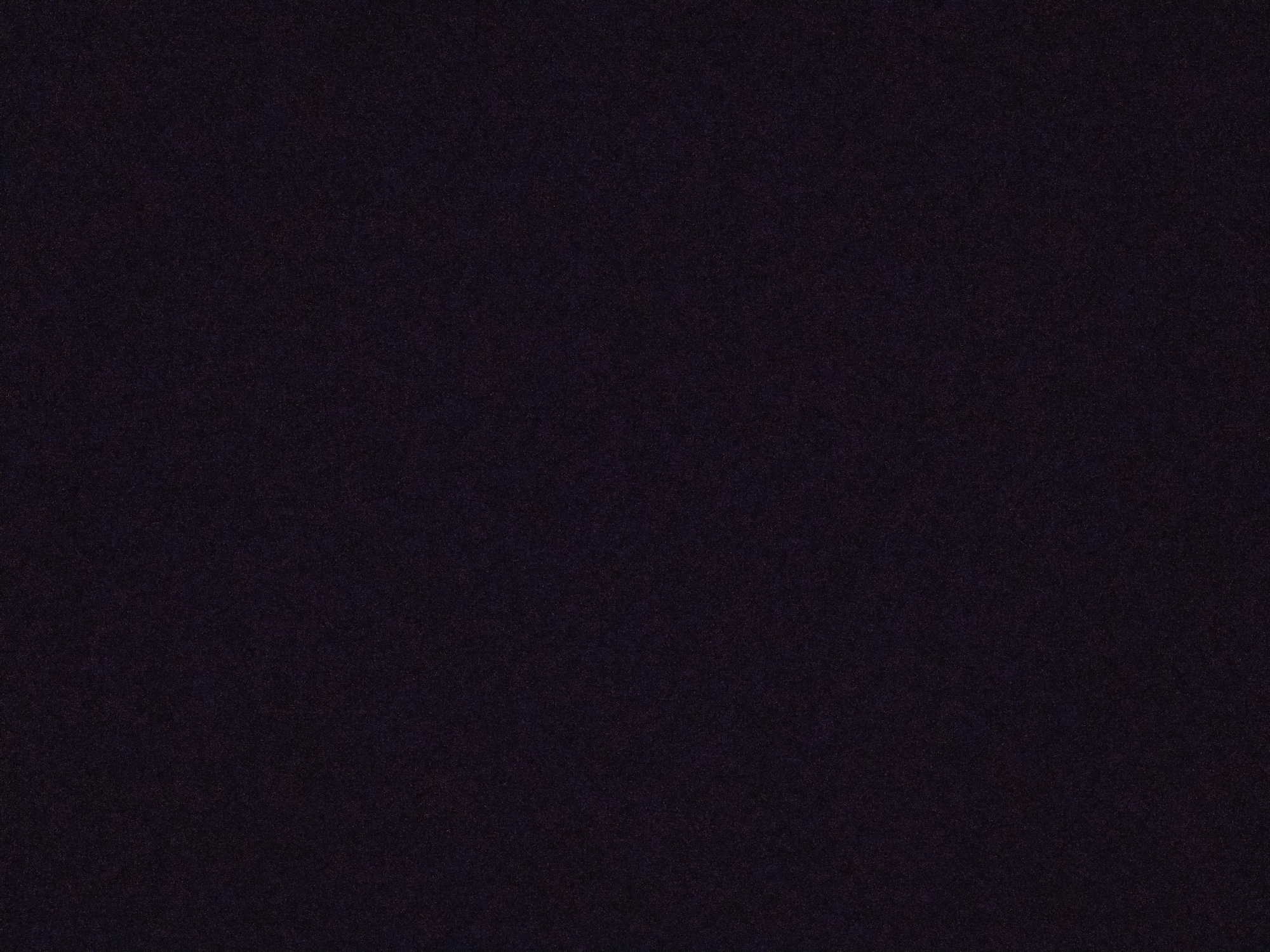The image is a dark, grainy texture. It is not possible to identify any specific location, people, objects, or activities. The environment is dark and undefined. There is no discernible information to describe the scene further.