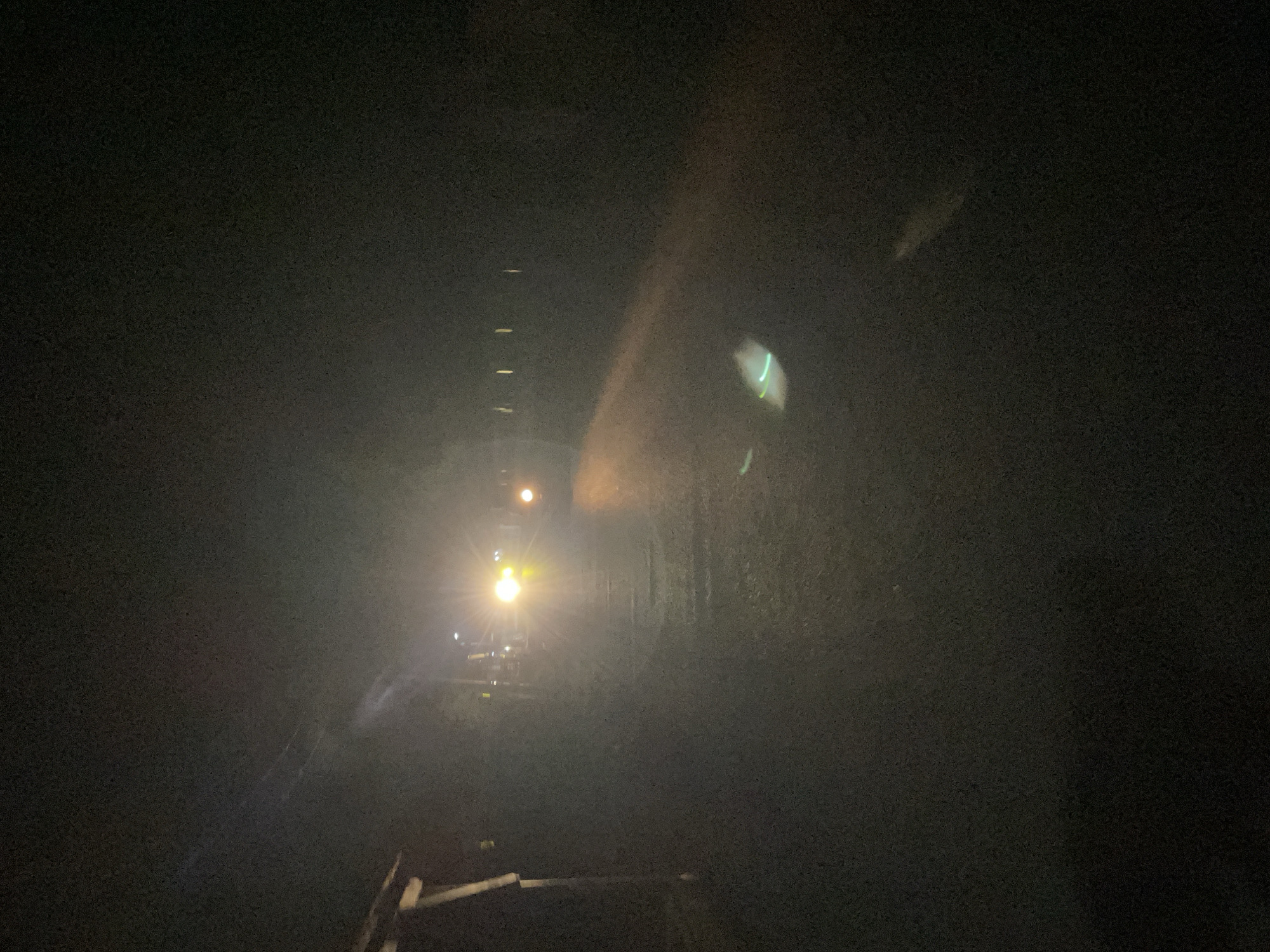 A nighttime view down a tunnel or mine shaft. A train's headlights shine in the distance. The location, Akwanga, Nigeria, is not clearly verifiable from the image content alone.