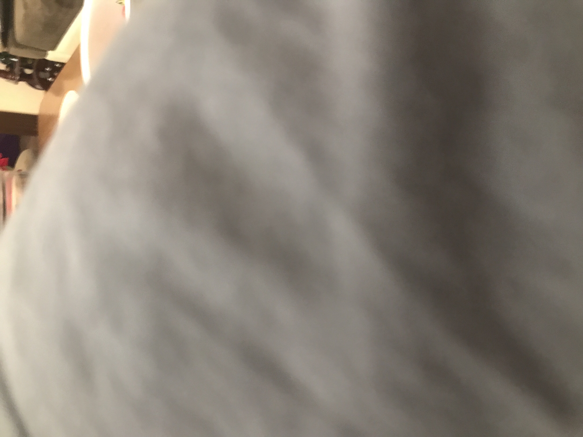 The image shows a blurred view of an interior scene, likely inside a shop or possibly a residence, due to the presence of furniture in the background. However, the foreground is dominated by a large, out-of-focus, possibly gray or white object, which obscures the details of the scene. The objects in the background appear to include parts of a chair and the edge of a table. The location cannot be determined from the image, but is presumed to be Yerevan, Armenia. No people, subjects, actions, or interactions are discernible from the available detail.