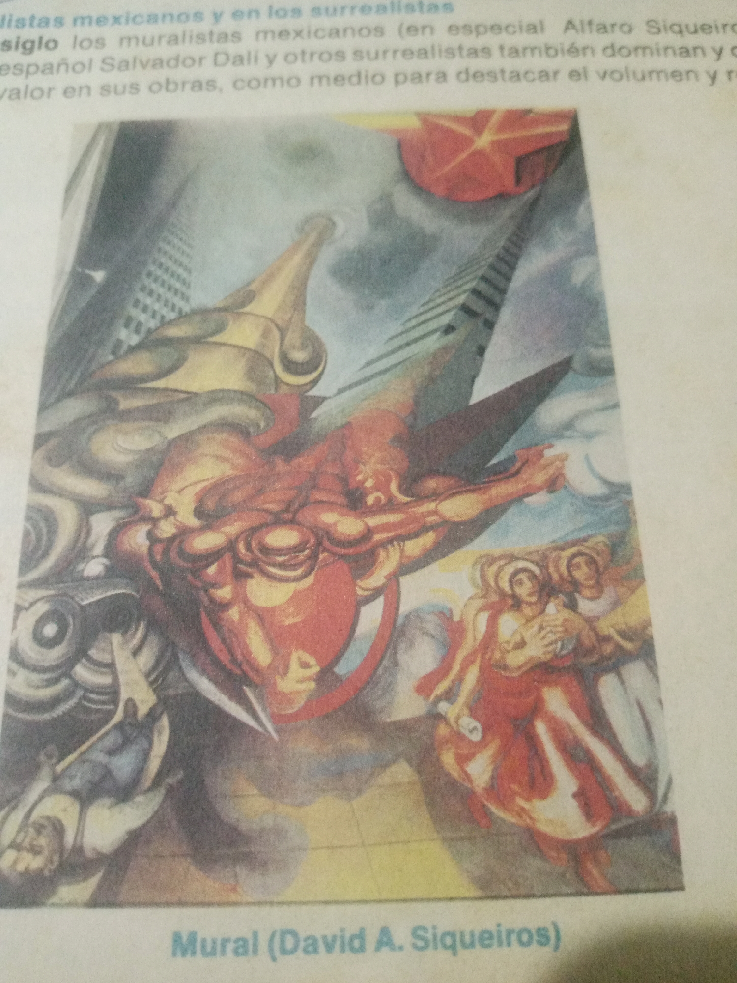 The image is a photograph of a mural painting, likely a reproduction from a book or magazine, as evidenced by the text at the top and bottom. The mural is a surrealist depiction featuring a large, winged, bull-like creature in the foreground, rendered in shades of red and yellow, with muscular anatomy. This creature appears to be emerging from or interacting with abstract architectural elements that resemble skyscrapers and a stylized, sun-like shape in red. To the right of the central creature, two figures, possibly women, are depicted wearing flowing red garments and appearing to hold a bird. Below this scene, text identifies the work as "Mural (David A. Siqueiros)". The text at the top of the image, in Spanish, discusses Mexican muralists and surrealism, mentioning David Alfaro Siqueiros. There is no information in the image or surrounding text that specifies a location in Santa Ana, Venezuela.