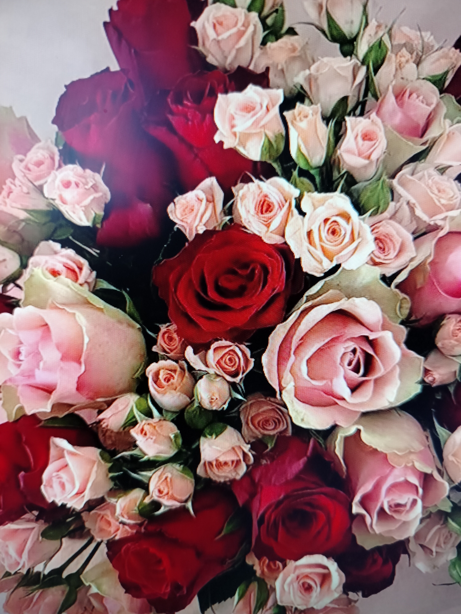 A bouquet of red and pink roses is depicted in a close-up, top-down view. The roses vary in bloom stage, with some fully open and others appearing as buds. The background is a light, neutral color, suggesting the bouquet might be placed against a wall or tablecloth. There are no people or animals visible in the image, and the scene is static. The image does not provide any information about a location in Yashkino, Russia.