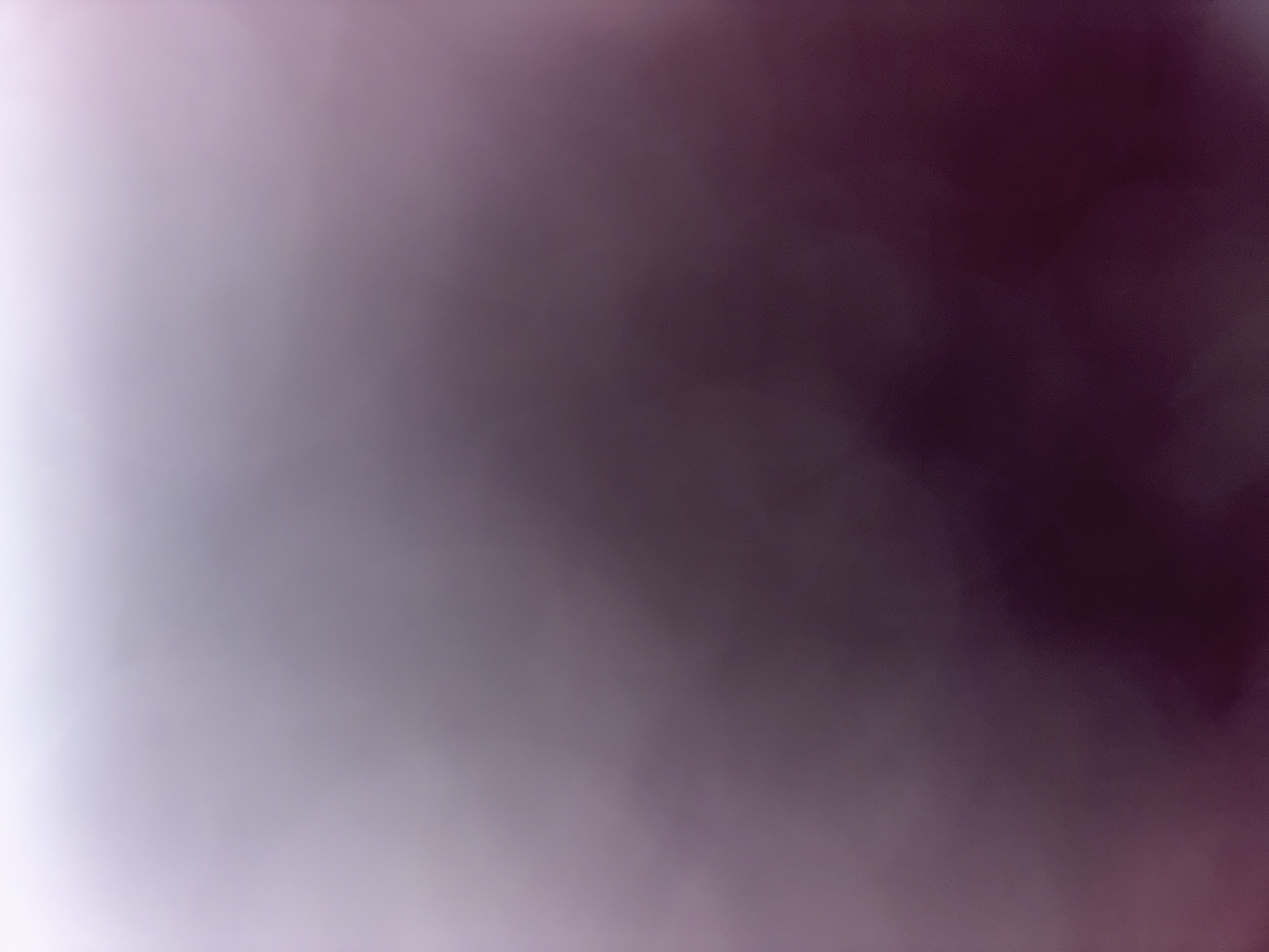The image is an out-of-focus shot with a color gradient ranging from white on the left to dark purple on the right. There are no recognizable people, objects, or locations visible in the image.