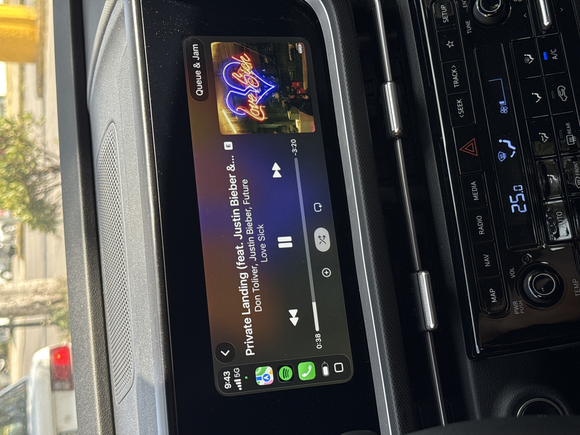The image shows the in-car infotainment system displaying music information. The song playing is "Private Landing" featuring Justin Bieber and Future, from the album "Love Sick." The display indicates the song is 38 seconds in, with 3 minutes and 20 seconds remaining. The top left corner shows the time is 9:43 AM, and the phone has 5G connectivity. The climate control system displays a temperature of 25.0 degrees. Adjacent to the screen are vehicle controls including A/C, fan speed, and navigation. The setting appears to be inside a car in Puebla, Mexico. The exact location within Puebla cannot be determined from the image.