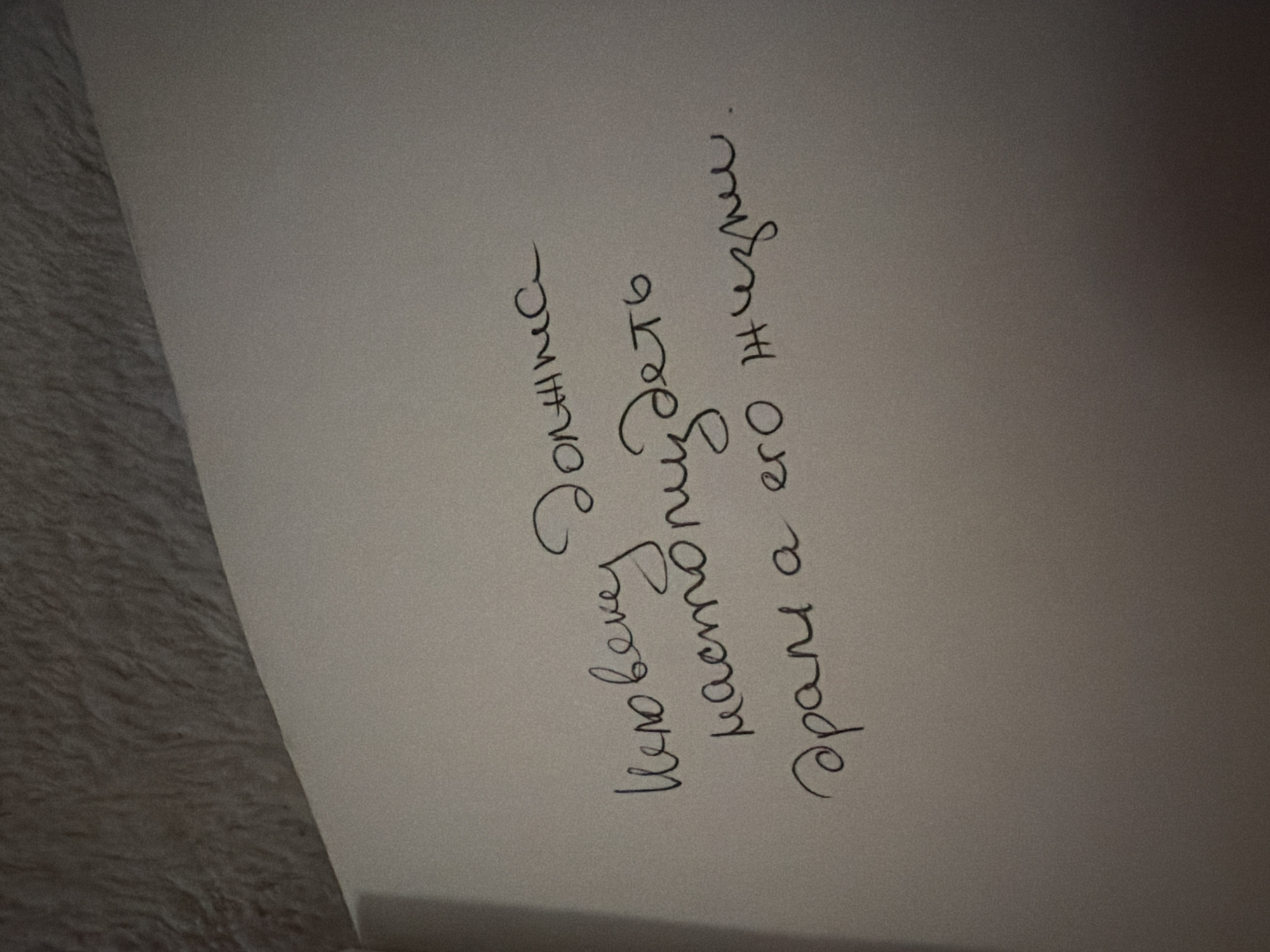 A piece of paper is shown with handwritten text in Russian. The text reads "Человеку должен настоящие врать а его жизни." (A person must truly lie to his life.)