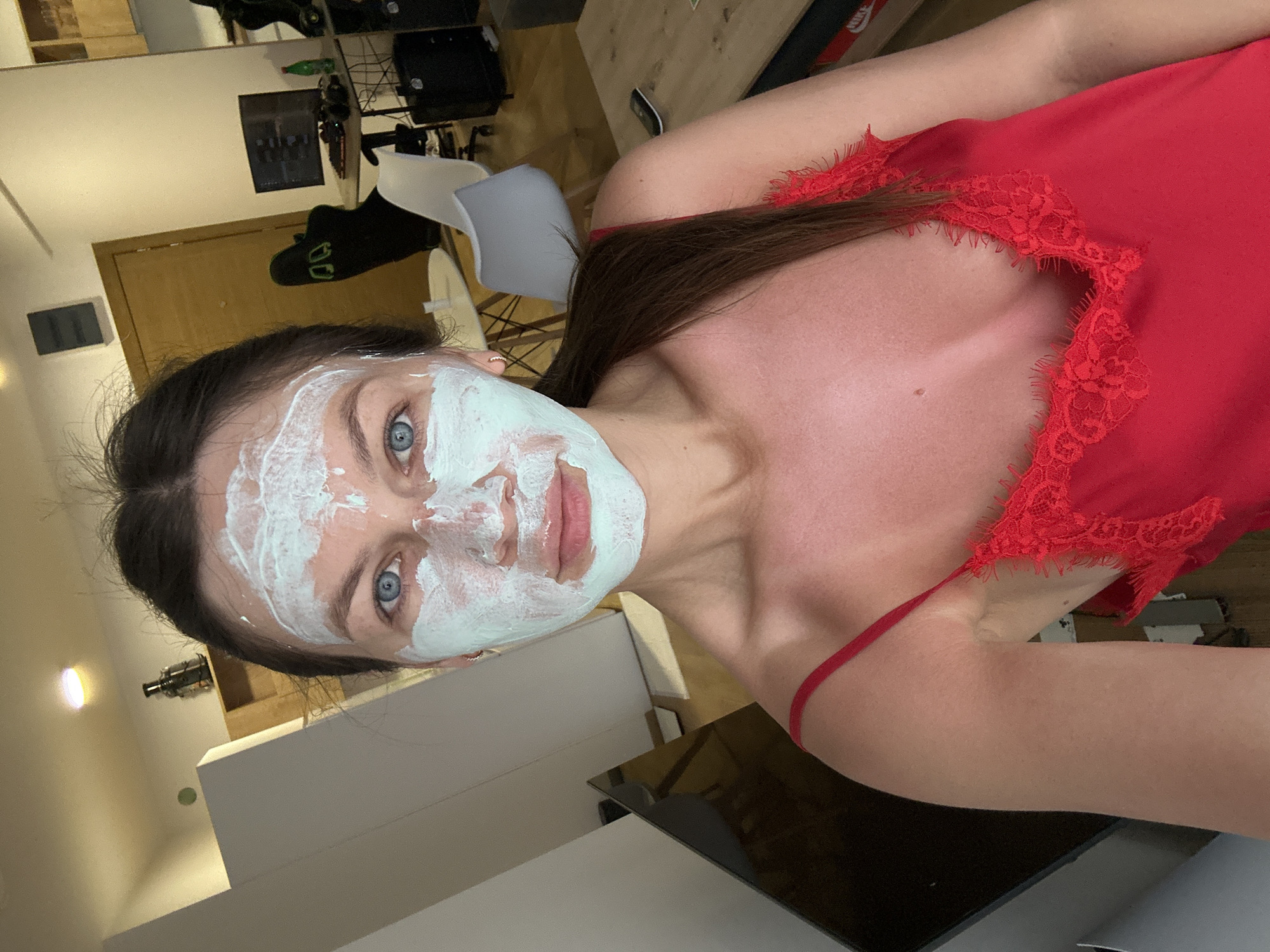 A woman with blue eyes has a white facial mask on. She is wearing a red lace-trimmed top. The location appears to be indoors. Additional context of Donji Pobori, Montenegro is not apparent in the image.