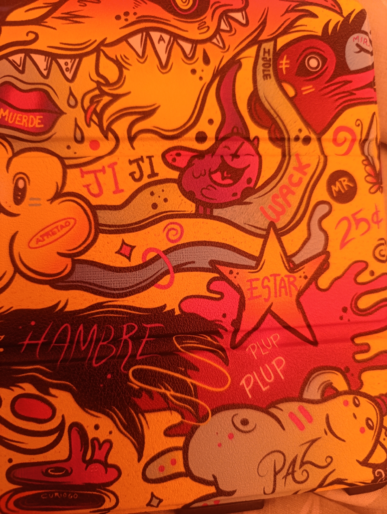 The image presents a densely populated, colorful doodle art composition. The palette is dominated by yellows, oranges, reds, and pinks. Words such as "MUERDE," "HAMBRE," "ESTAR," "PLUP," "PAZ," and "WACK" are interspersed within the illustrations. There are cartoonish depictions of faces, including a monster-like creature with sharp teeth, a smiling character, and animals. Additional details include a star shape, the number "25¢," and other symbols and shapes. The overall style suggests a lighthearted, playful aesthetic. The location of Зипуново, Russia is not discernible from the image.