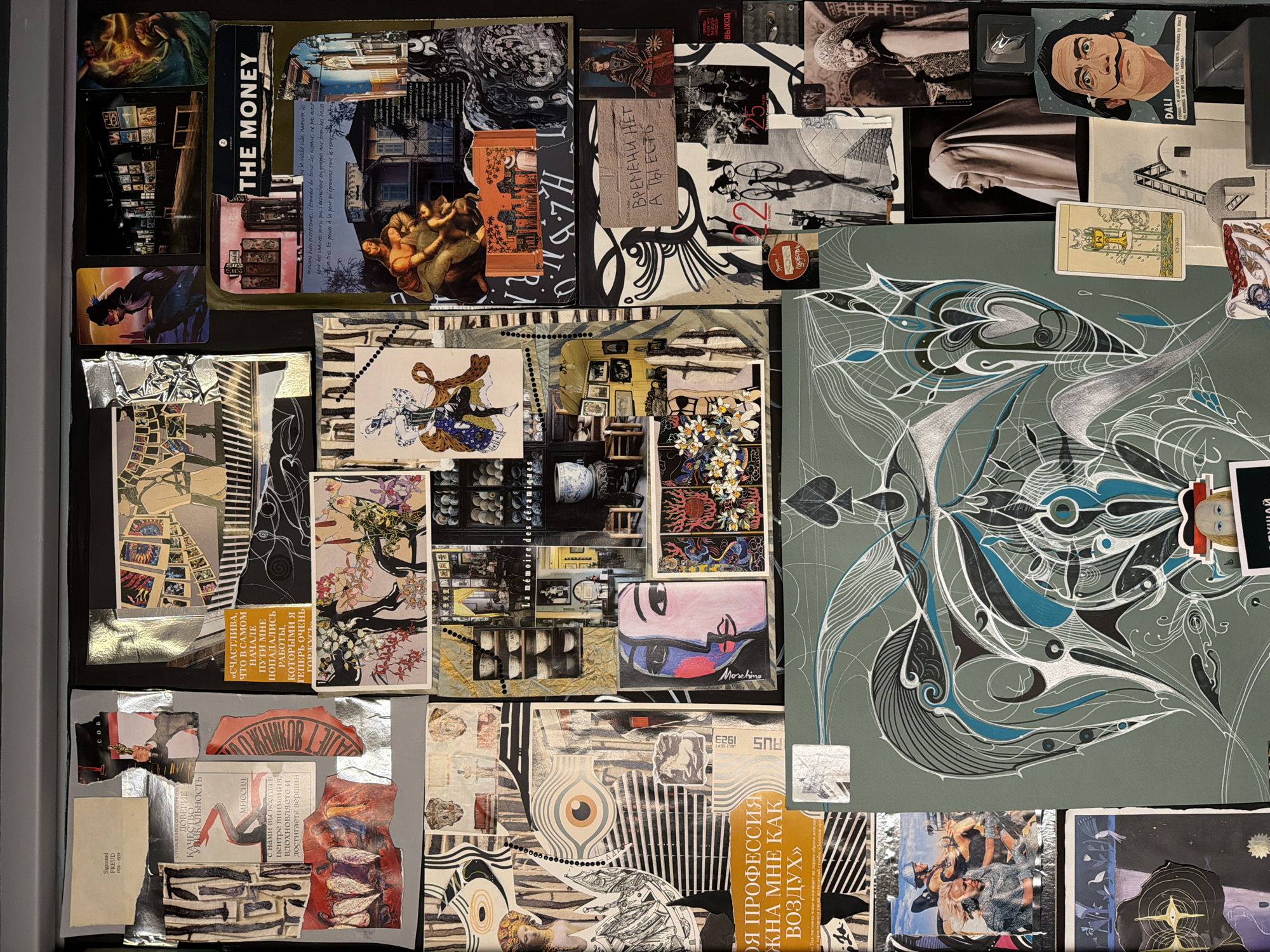 This is a collage on a dark grey surface, likely a bulletin board, containing various cut-out images and texts.
The top left corner features images of art, a building, and a book cover with the title "THE MONEY". Moving right, there are black and white photographs, art pieces, and a caricature of Salvador Dali. A tarot card is included among the images.
In the middle section, there is a mix of photographic images including interiors, portraits, and graphic designs.
The lower portion displays art, text in Cyrillic script including the name "Sigmund Freud", and fragments of illustrations.
A large illustration in shades of grey, black, and blue dominates the right half of the collage.
The elements appear to be cut from various sources, including books, magazines, and art prints, and are arranged on the surface in a seemingly random manner. There's no clear indication of a specific location or connection to Moscow, Russia.