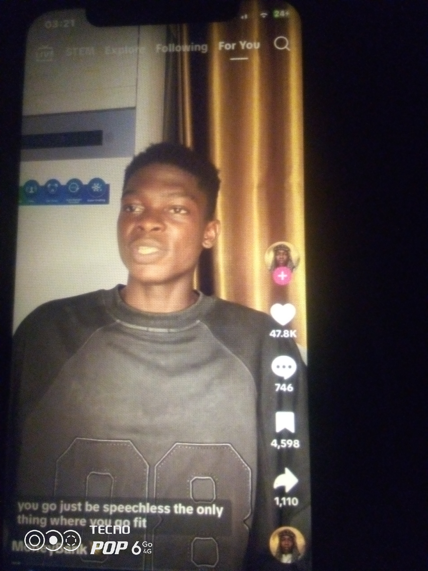 The image is a screenshot of a TikTok video being viewed on a smartphone. The video features a young Black male speaking directly to the camera. He is wearing a dark gray crewneck sweatshirt with a graphic design of the number "88" on it. The background of the video appears to be a golden, pleated curtain. On the right side of the screen, there are typical TikTok interface elements, including a profile picture of the creator, a heart icon with "47.8K" likes, a speech bubble icon with "746" comments, a bookmark icon with "4,598" saves, and a share icon with "1,110" shares. At the bottom of the screen, there is text overlay that reads "you go just be speechless the only thing where you go fit" and a Tecno Pop 6 Go logo. The smartphone screen displays the time "03:21" at the top left and "24%" battery life at the top right. The overall image quality is low, suggesting it was taken in low light conditions or with a low-resolution camera. The location of Howayi, Nigeria is not discernable from the visual information in the image.