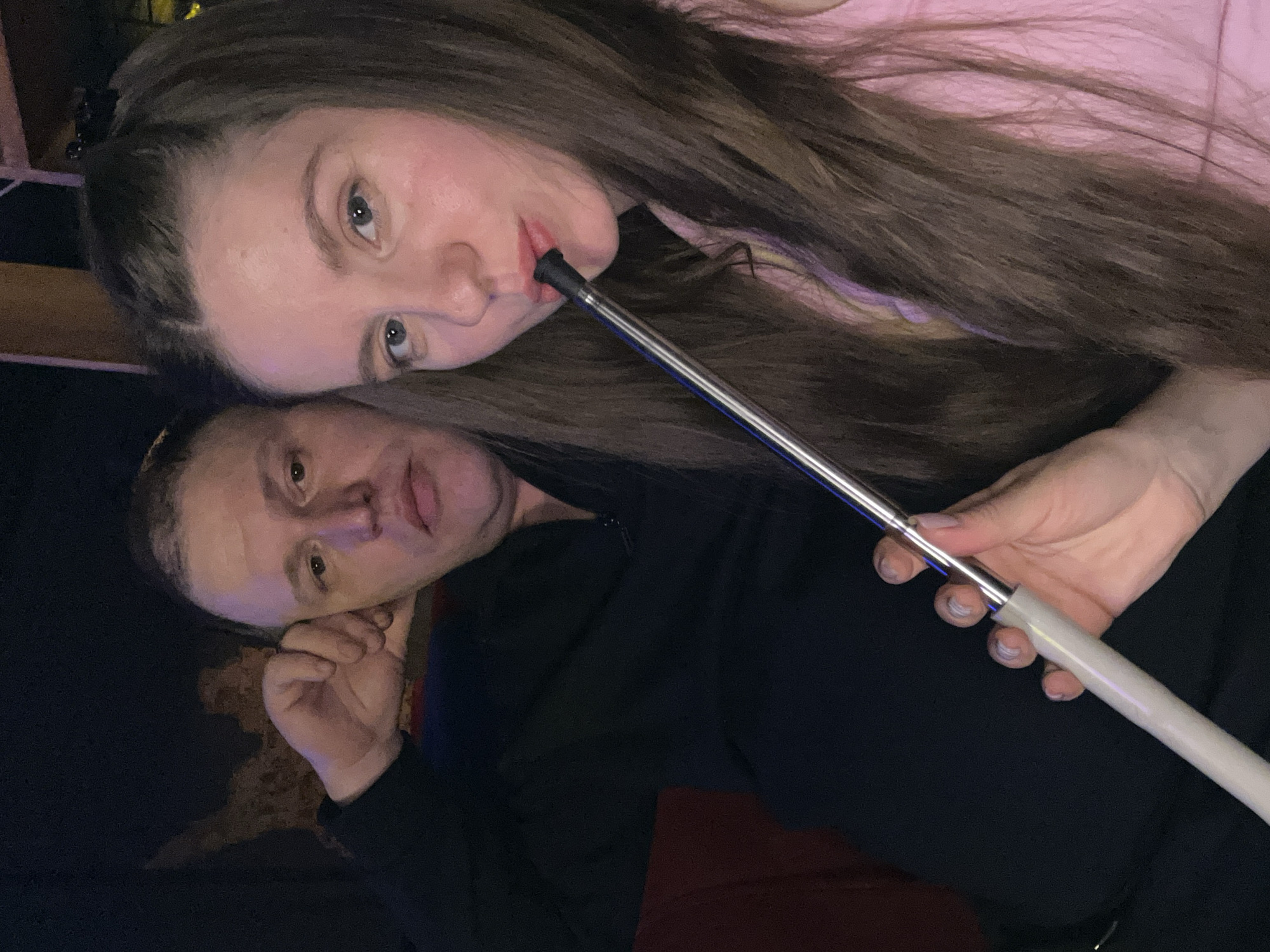 A woman with long brown hair wearing a pink top holds a hookah hose to her lips. Next to her is a man in a black shirt. The location is assumed to be Klin, Russia.