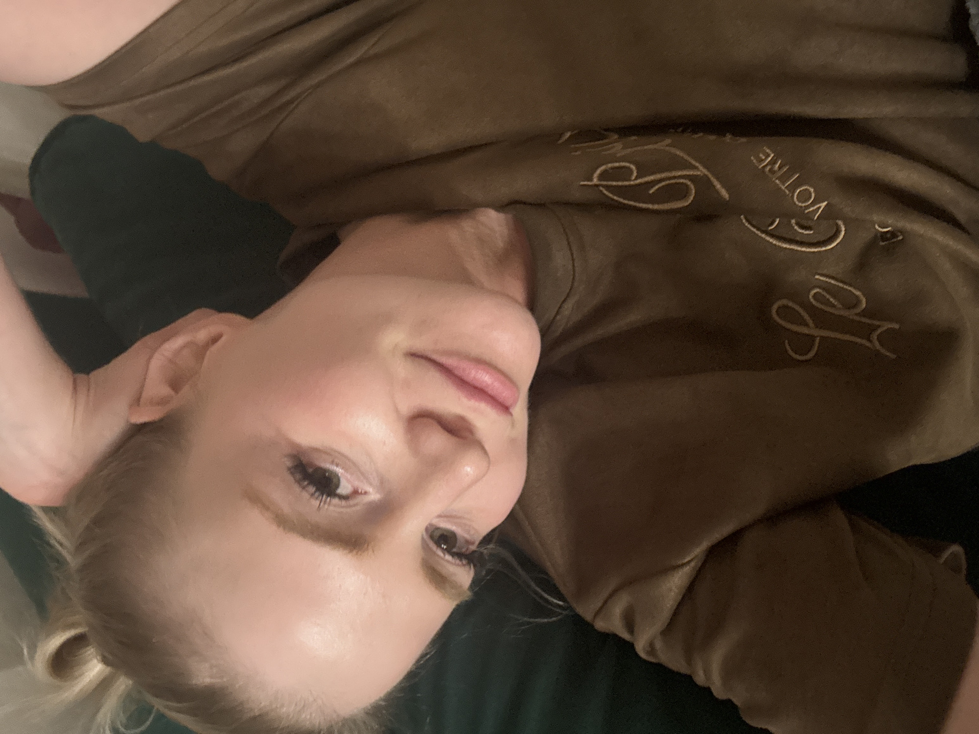 A woman with fair skin and light blonde hair, partially obscured by a t-shirt with the words "Le Votre" embroidered on it, is lying down. The background appears to be dark green. The location, Saint Petersburg, Russia, cannot be determined from the visual information provided.