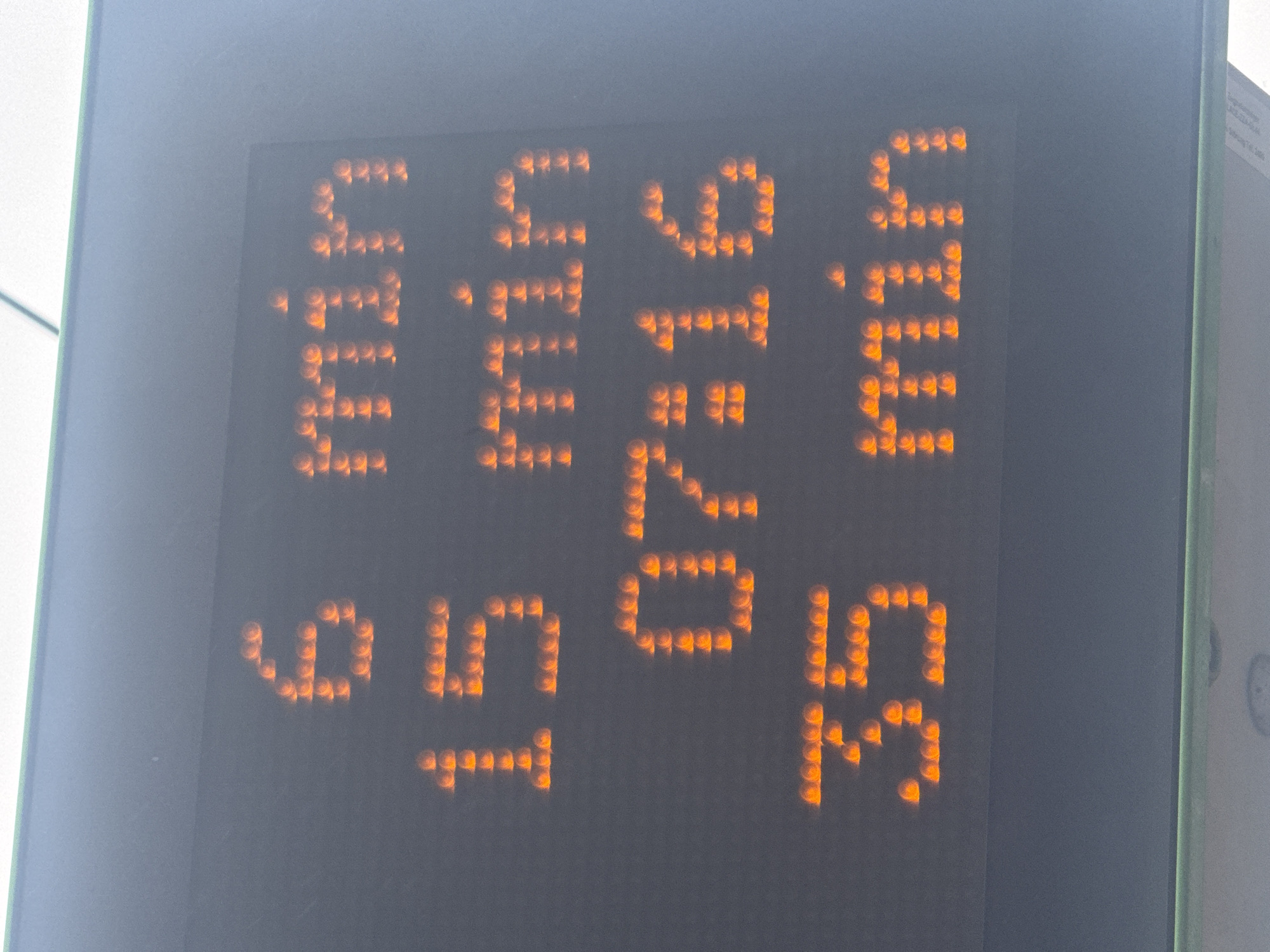 A close-up, vertical, eye-level shot shows an electronic display board with amber LED lights. The display shows three lines of text. The top line reads "6 min". The second line reads "15 min". The third line displays "07:16". The bottom line reads "35 min". The display board is set against a dark, textured background, and a hint of a green border is visible at the very top and bottom of the image. The image appears to be taken outdoors, likely in a public transportation setting, although the specific location is unknown.