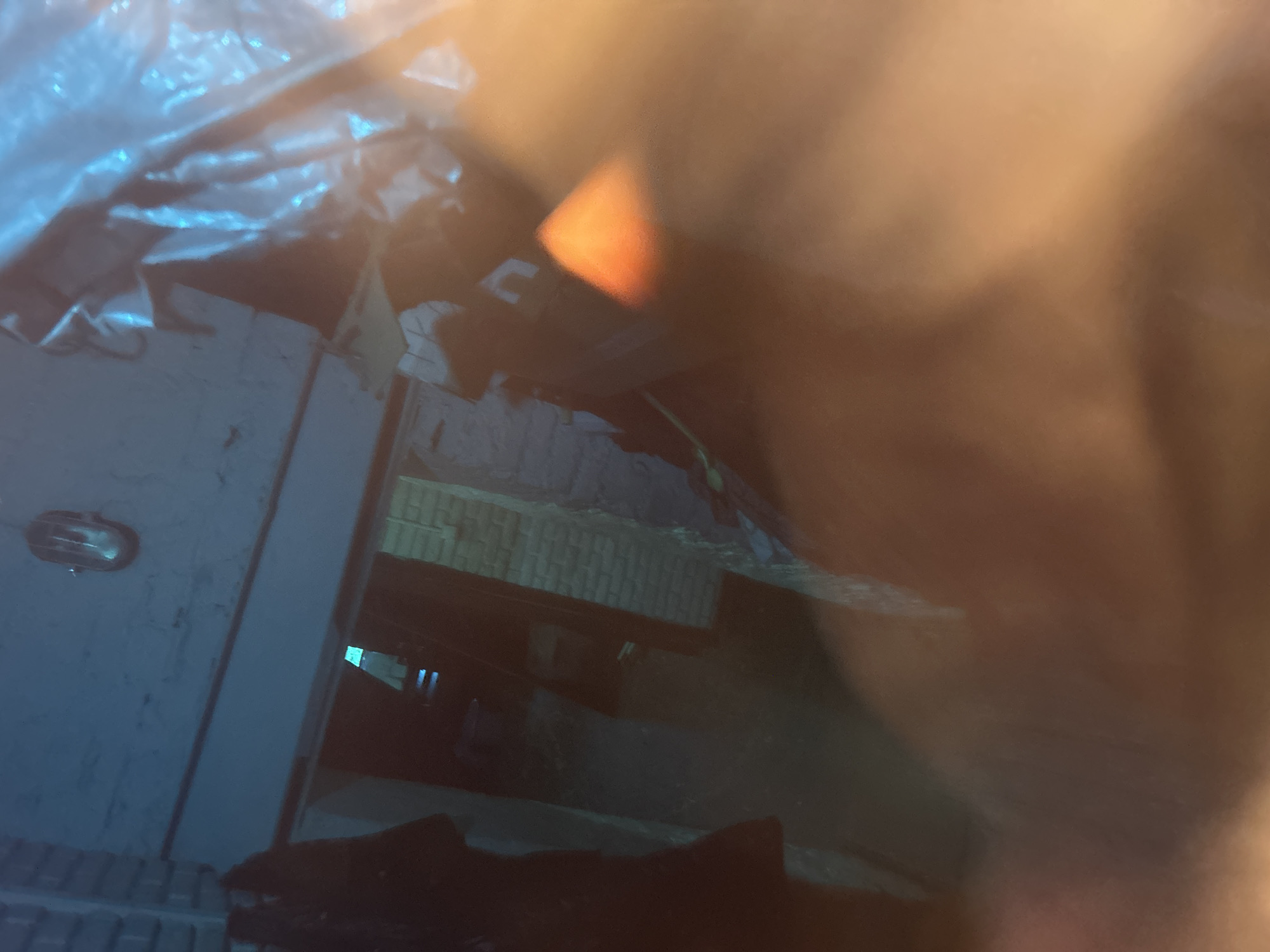 The image appears to be an indoor scene, possibly within a building, in Unknown, Unknown. The background shows a brick or cinder block wall. A light fixture is visible on one of the walls. The lighting is dim, and parts of the scene are blurry or obscured.